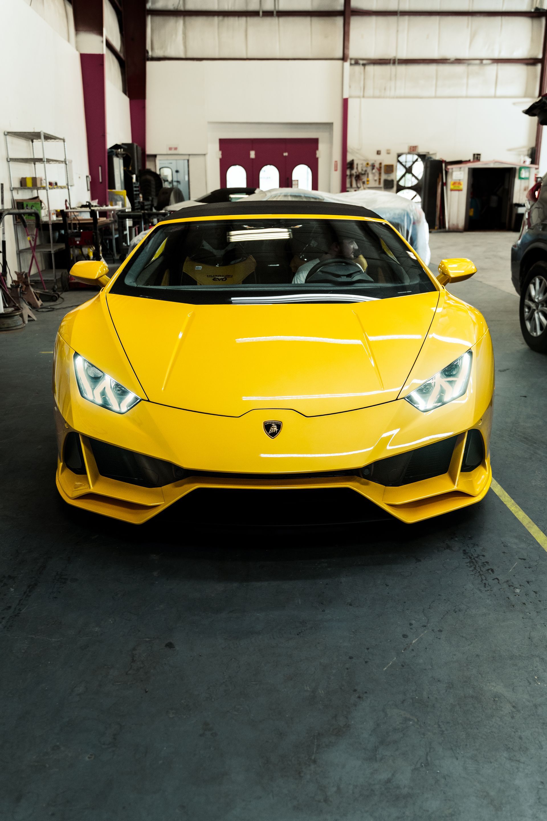 Yellow Lamborghini sports car parked in a garage, front view.