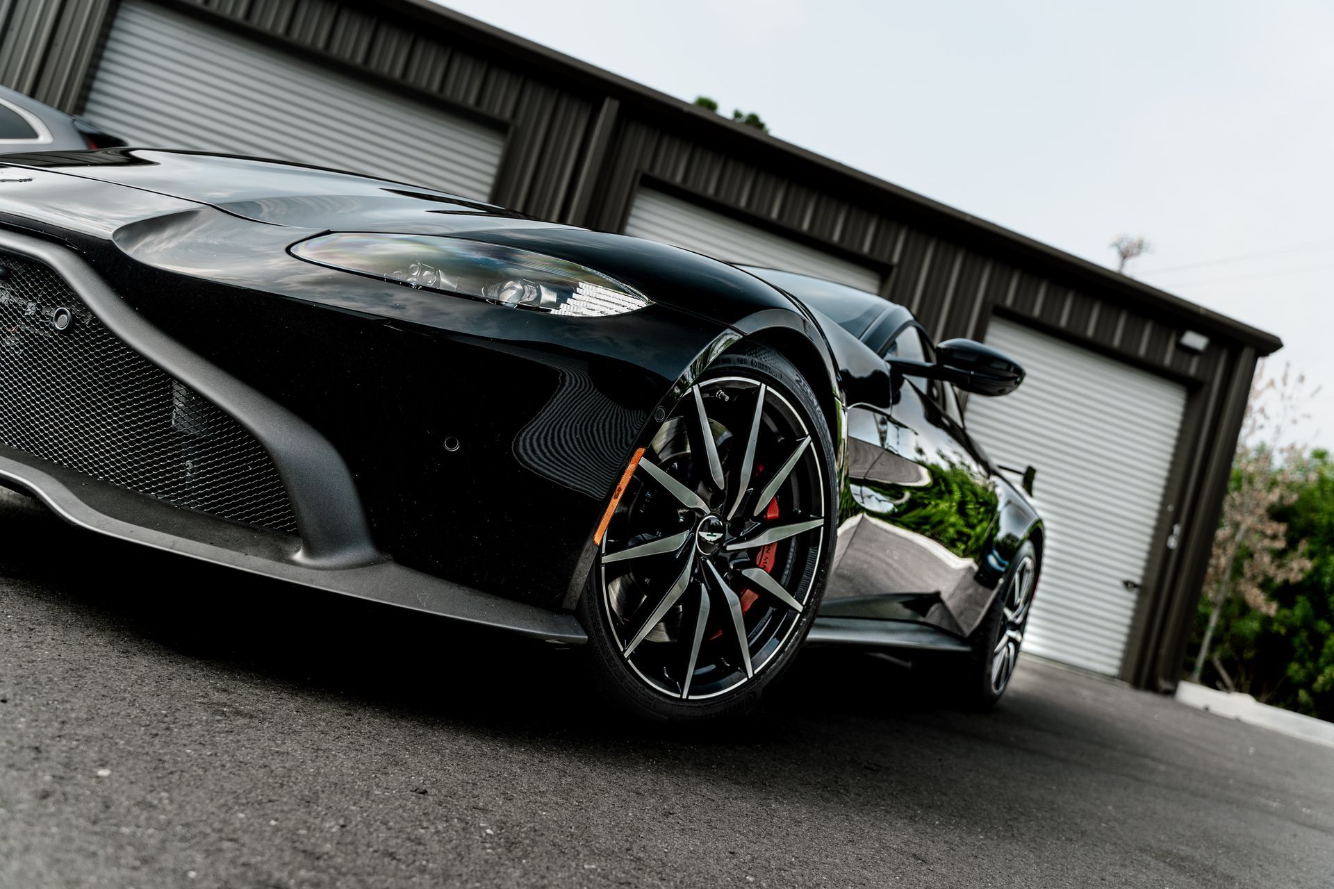 Black sports car parked in front of a garage, low-angle view on a wet driveway
