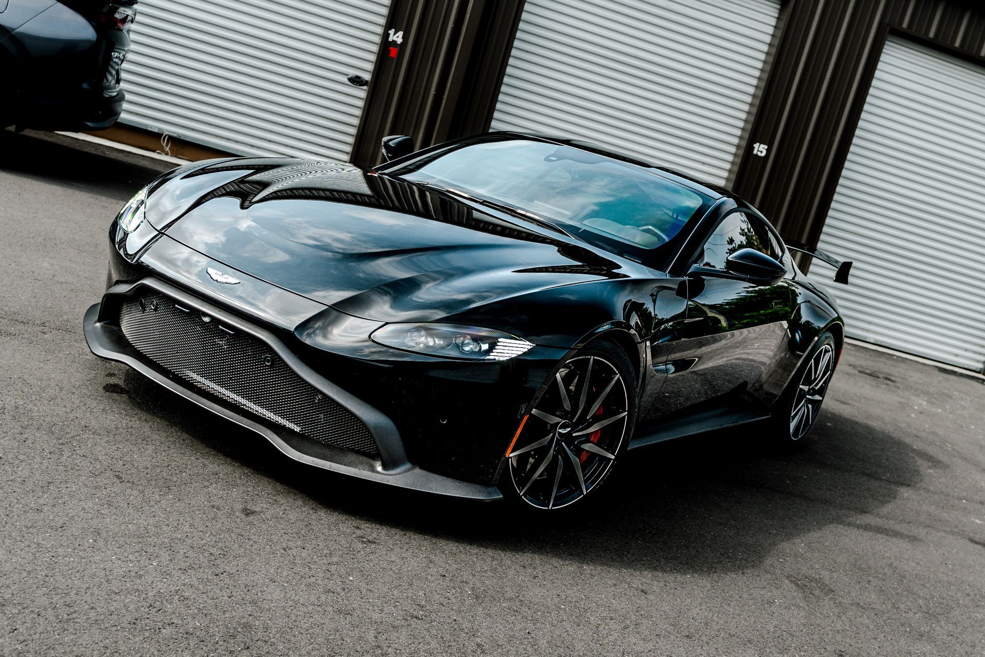 Black sports car parked on a street in front of industrial garage doors