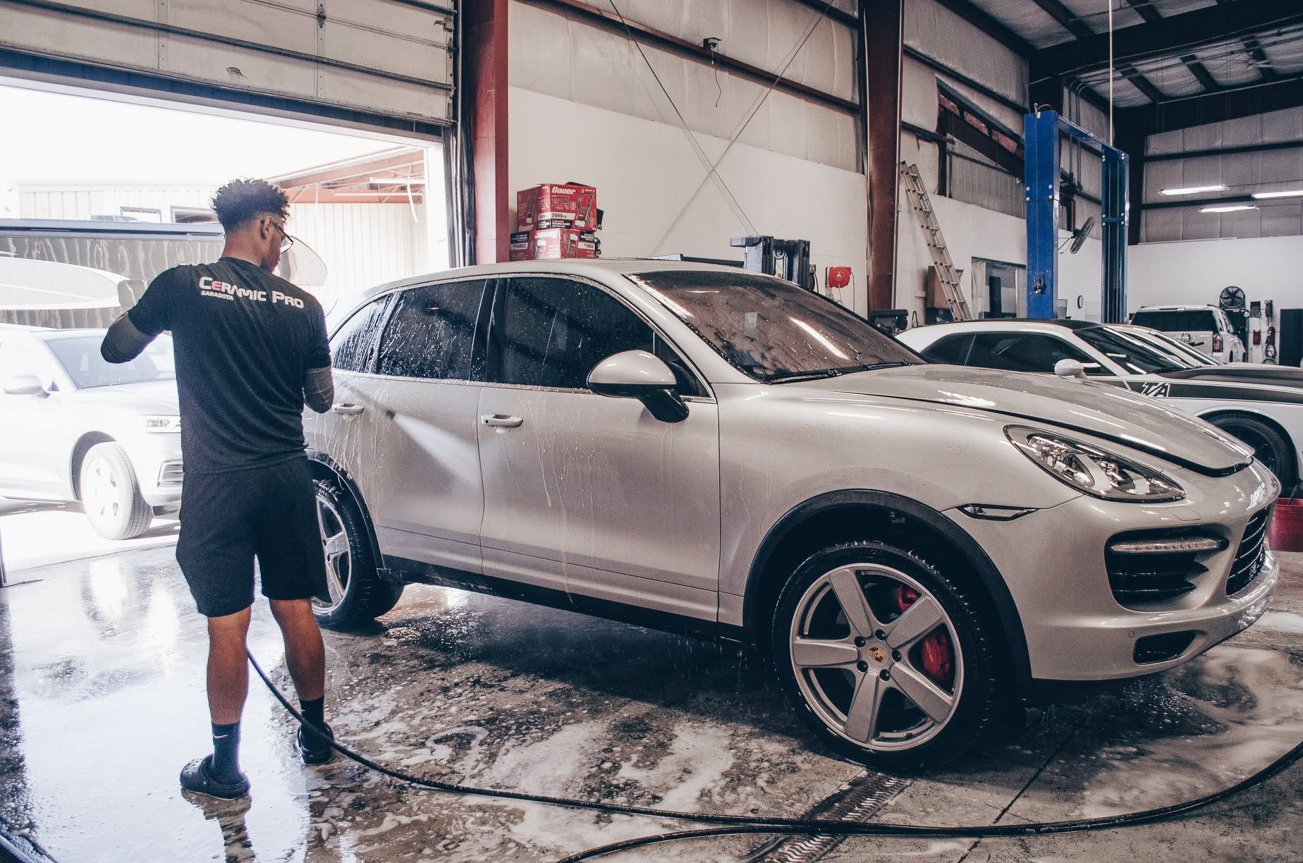 Man washing a silver SUV in an auto detailing garage