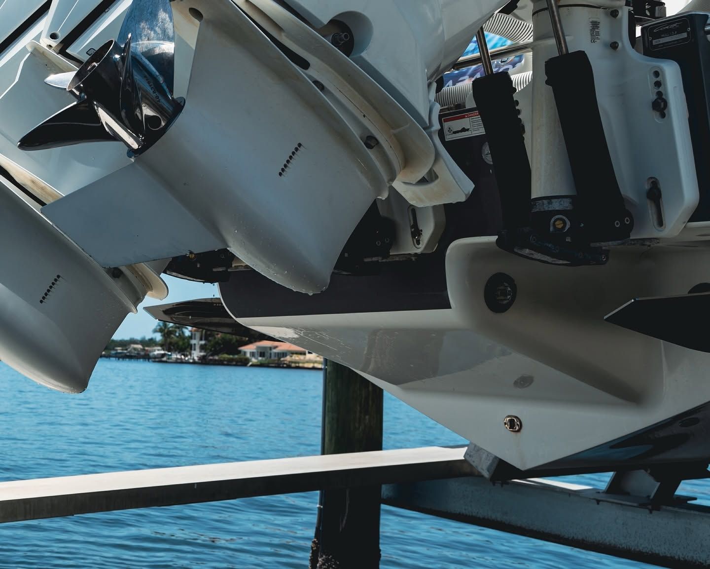 White boat motors mounted on a dock beside calm blue water under a clear sky