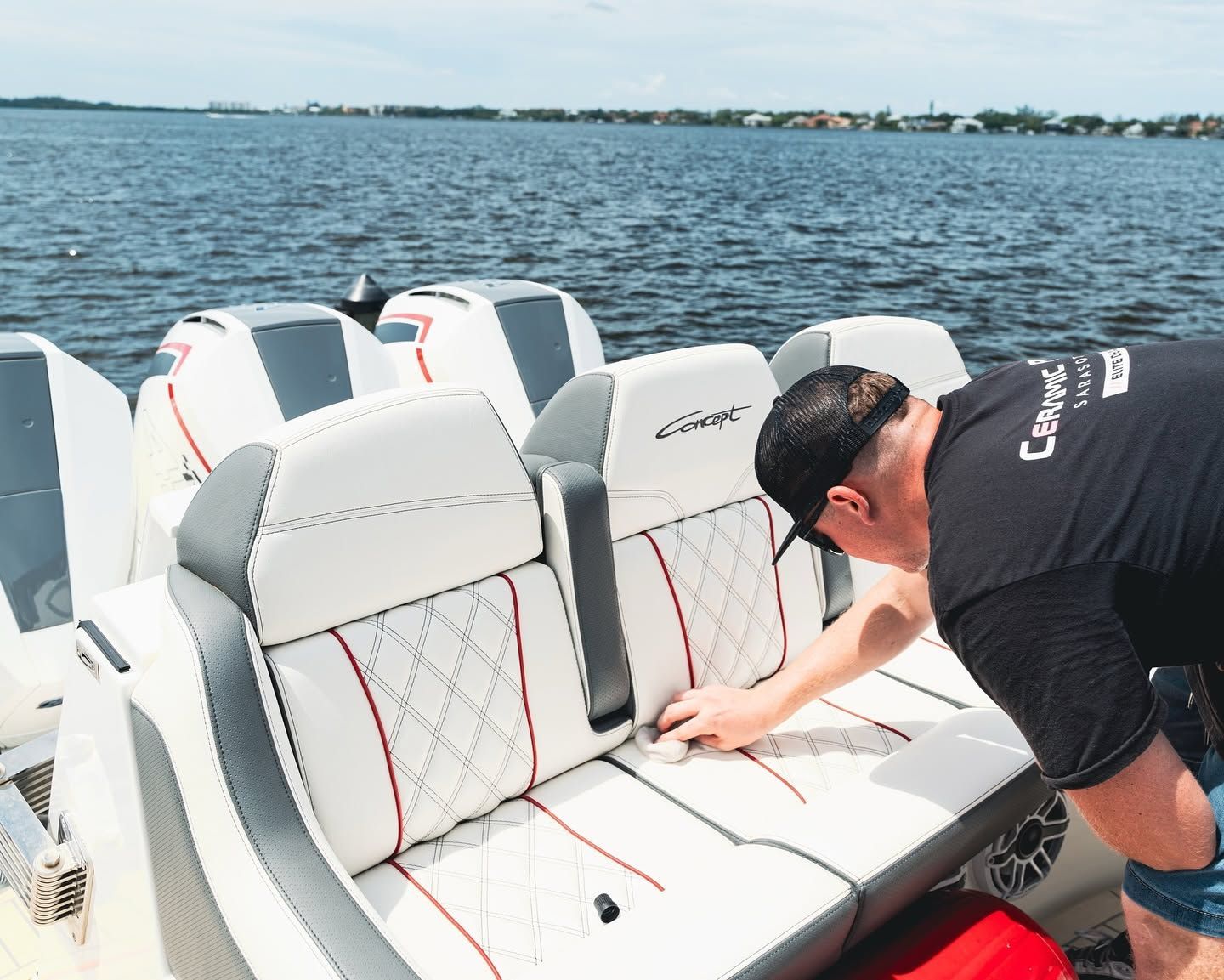 Man inspecting white boat seats on a yacht with open water in the background