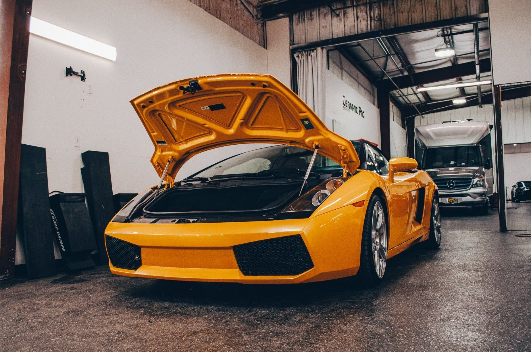 Yellow sports car with open hood parked in a garage