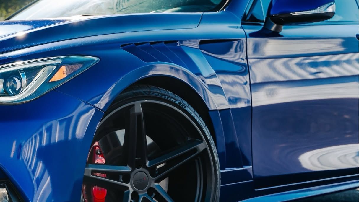 Blue sports car with black alloy wheel and red brake caliper in a close-up side view