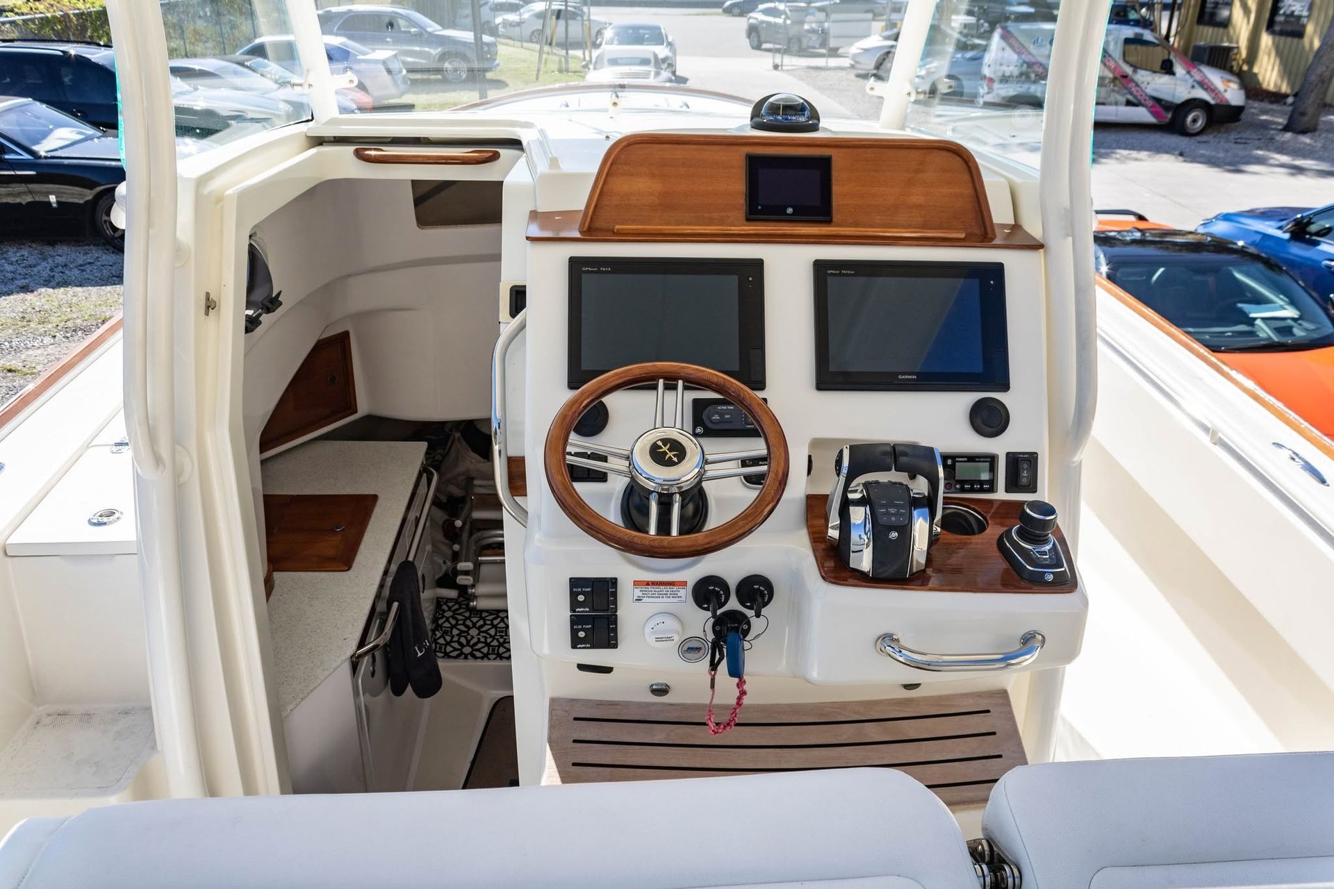 Boat cockpit with steering wheel, navigation screens, and wood-trim dashboard at a marina