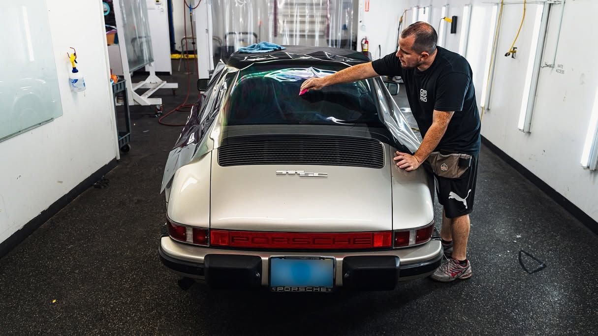 Man washing a beige sports car inside a car wash tunnel