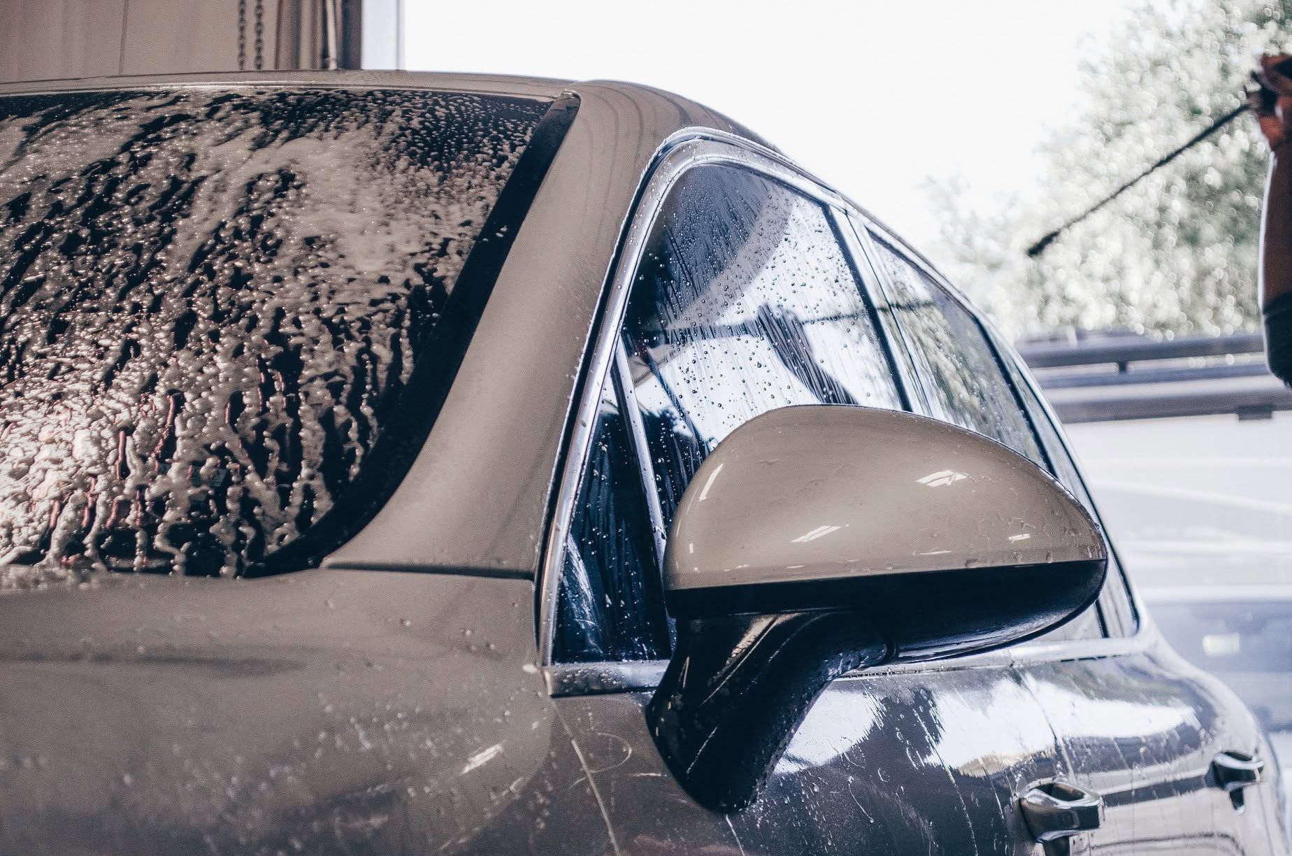 Snow-covered car side mirror and window on a dark vehicle