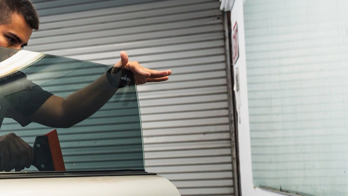 Person extending an arm beside a white garage door and window blinds