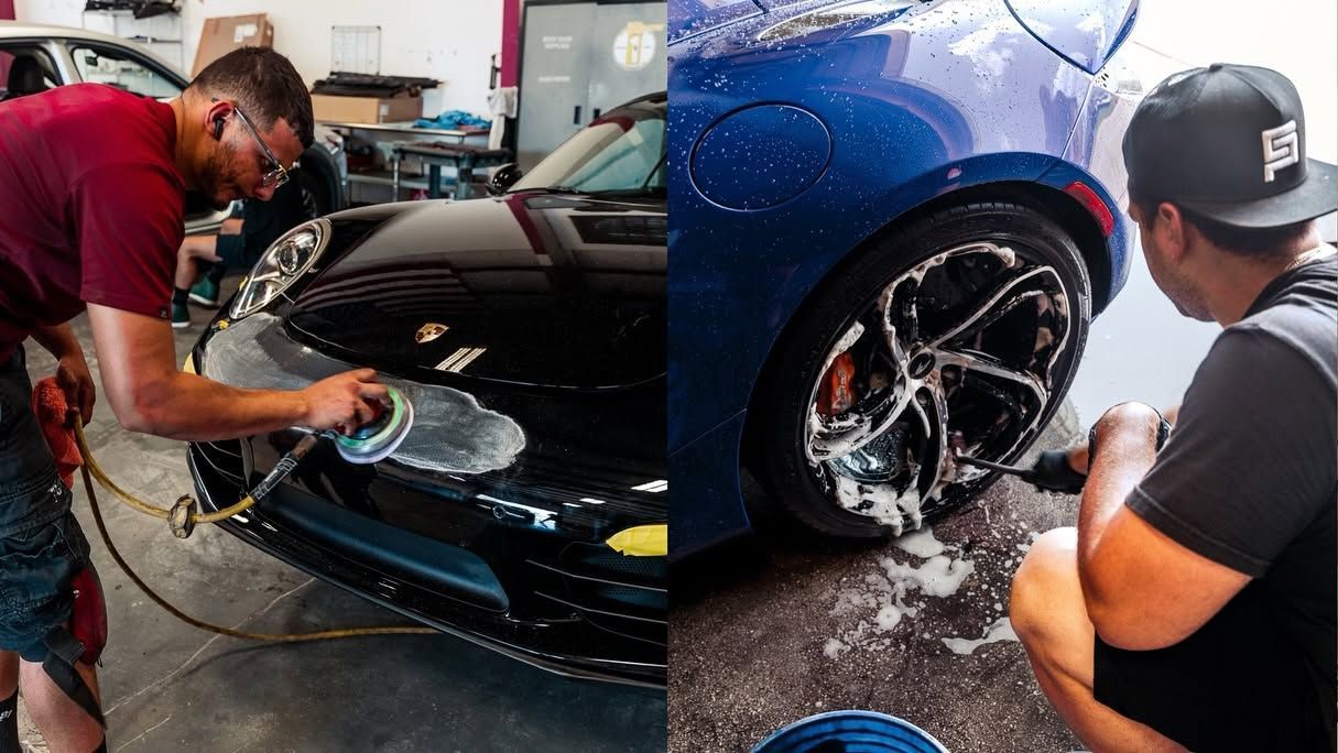Two people washing a dark blue sports car in a garage, with soap and water on the hood.
