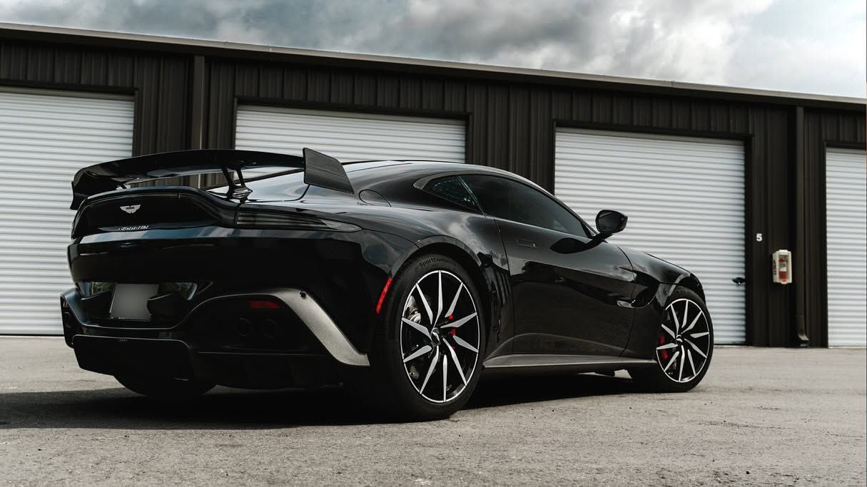Black sports car parked outside industrial garage doors