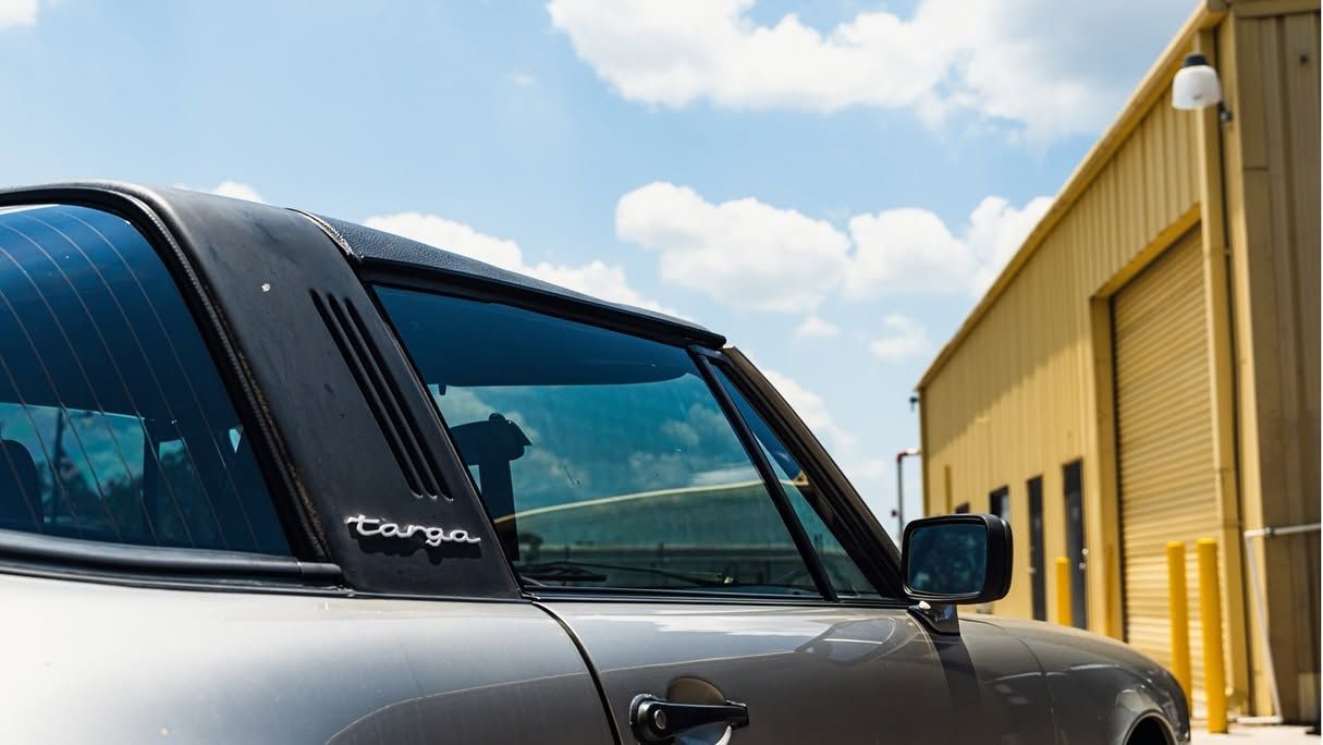 Silver truck parked beside a yellow industrial building under a blue sky.