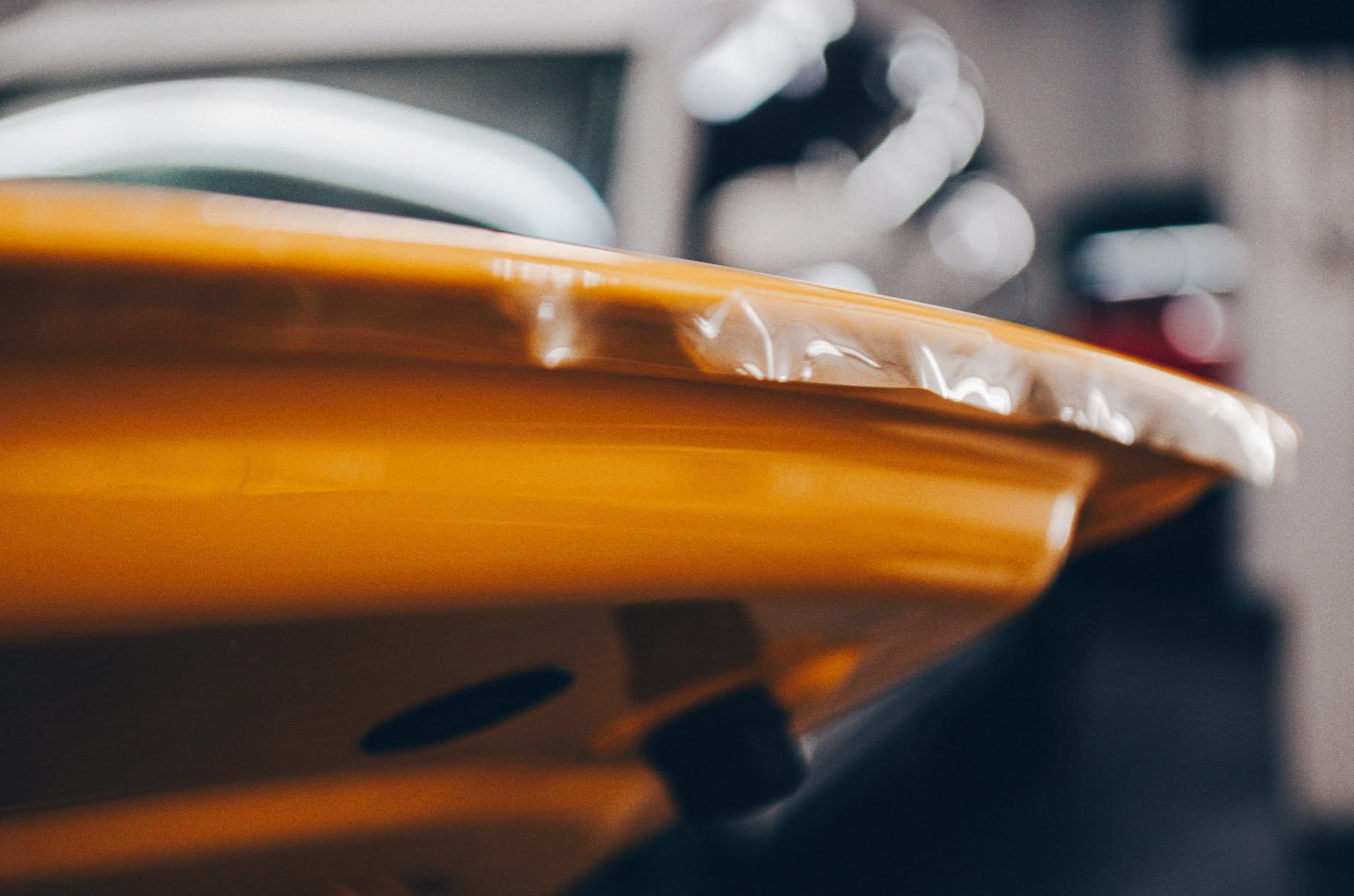 Close-up of a glossy orange car body panel with blurred background