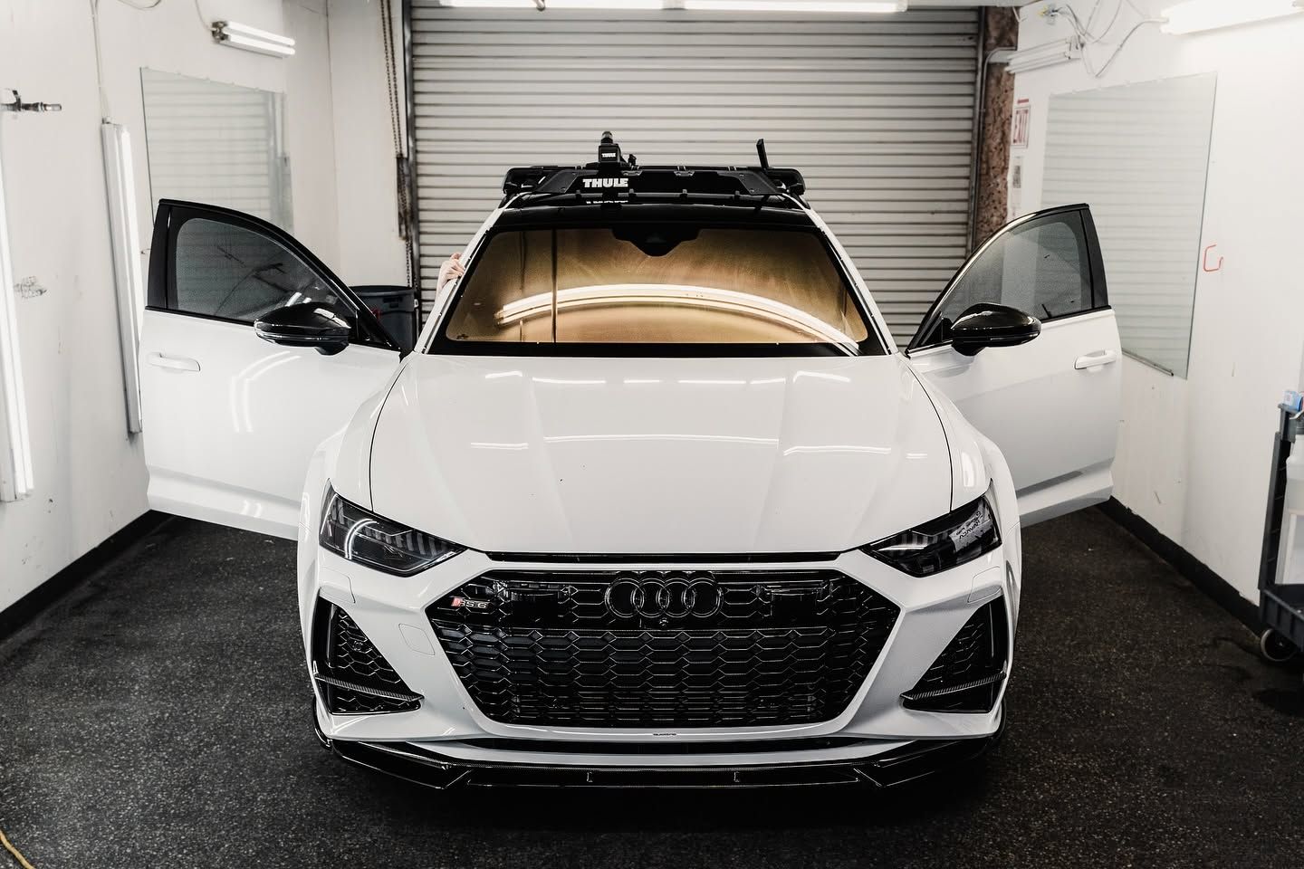 White Audi SUV in a garage with both front doors open.