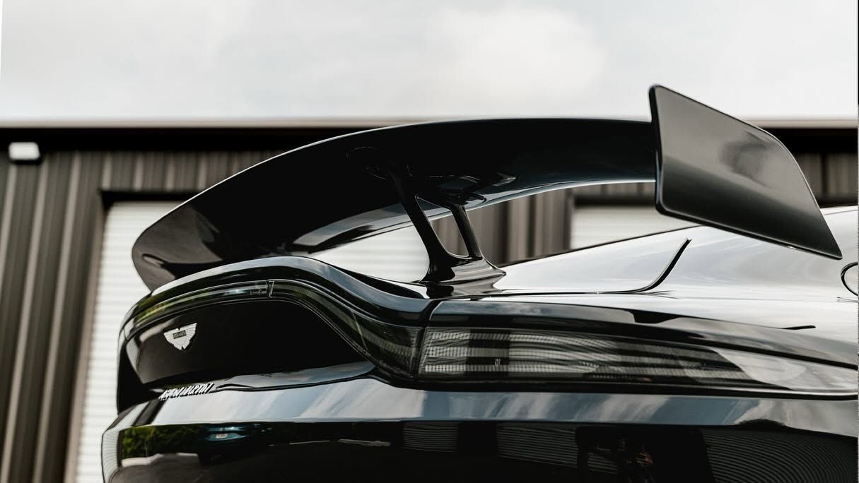 Rear view of a black sports car with a large spoiler parked in a garage