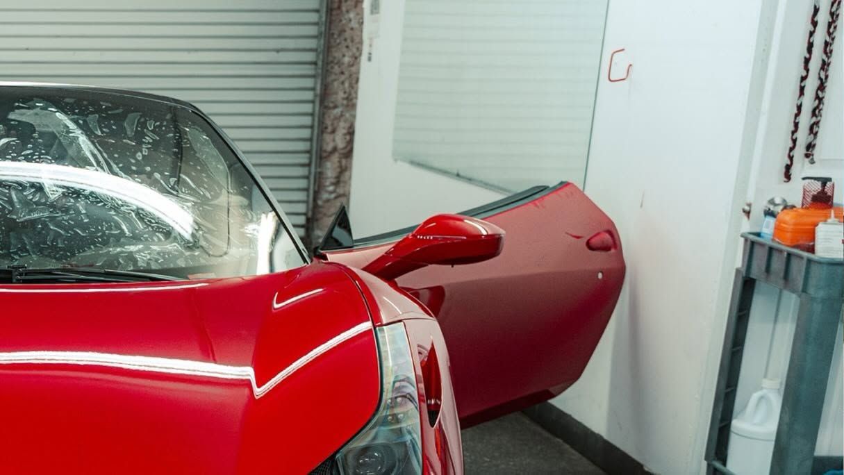 Red sports car with open door in a garage or workshop