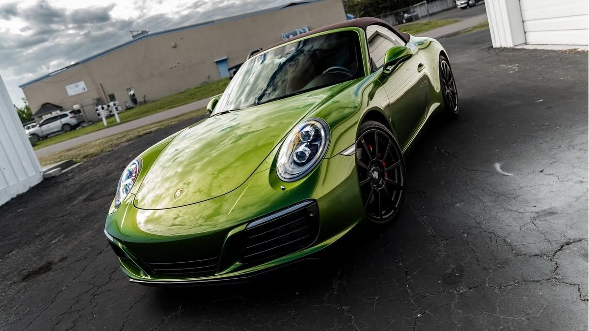 Lime green sports car parked in a garage doorway on a wet pavement