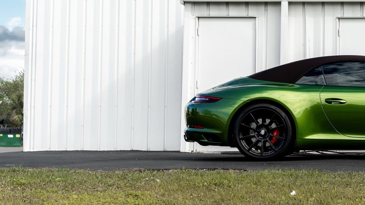 Green sports car parked beside a white building