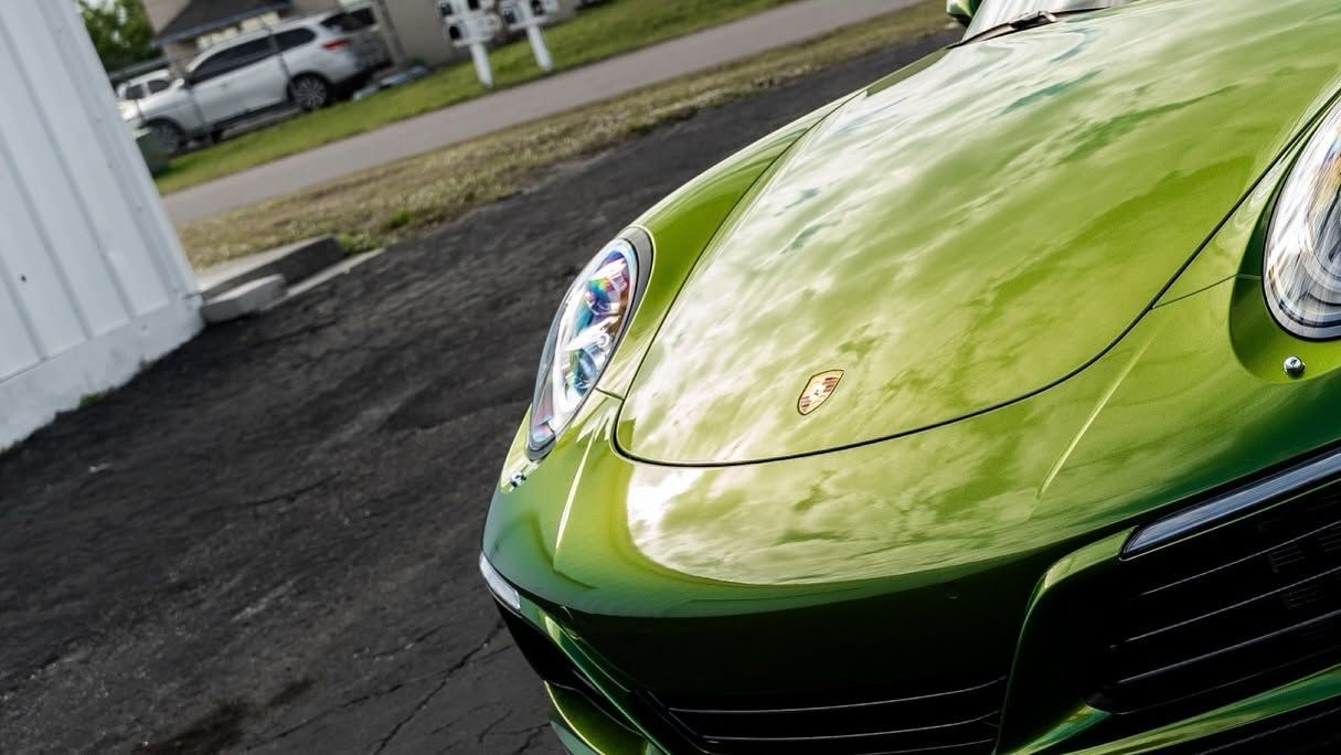 Close-up of the front of a lime-green sports car parked on a driveway.
