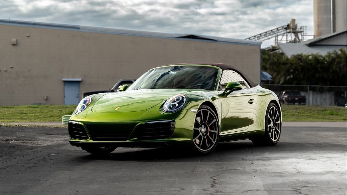 Lime green sports car parked on wet pavement in front of a gray building