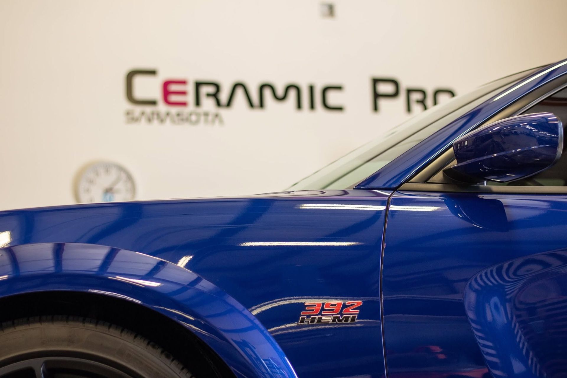 Blue sports car in front of a Ceramic Pro sign