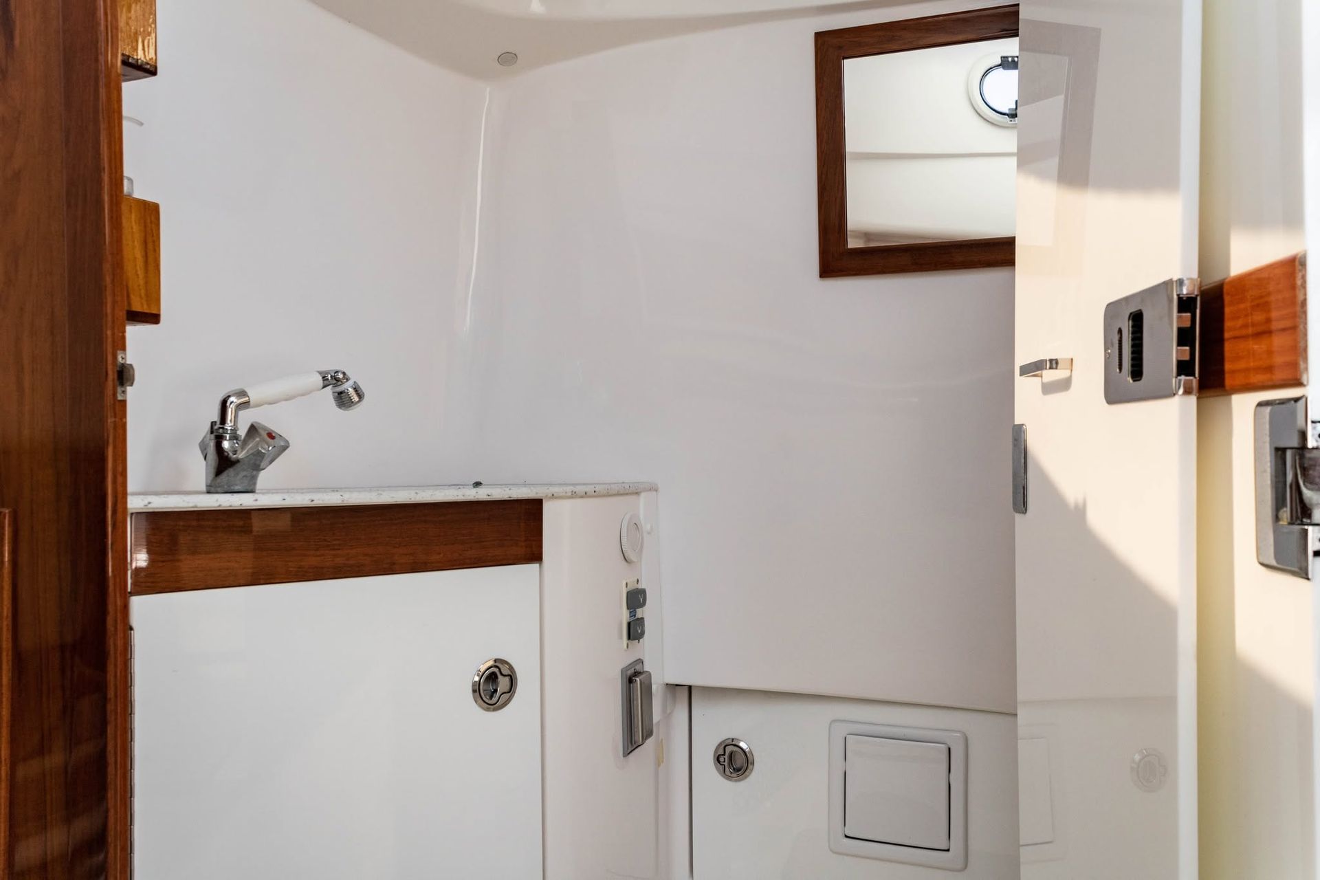Small white bathroom with sink, mirror, cabinet, and open door.