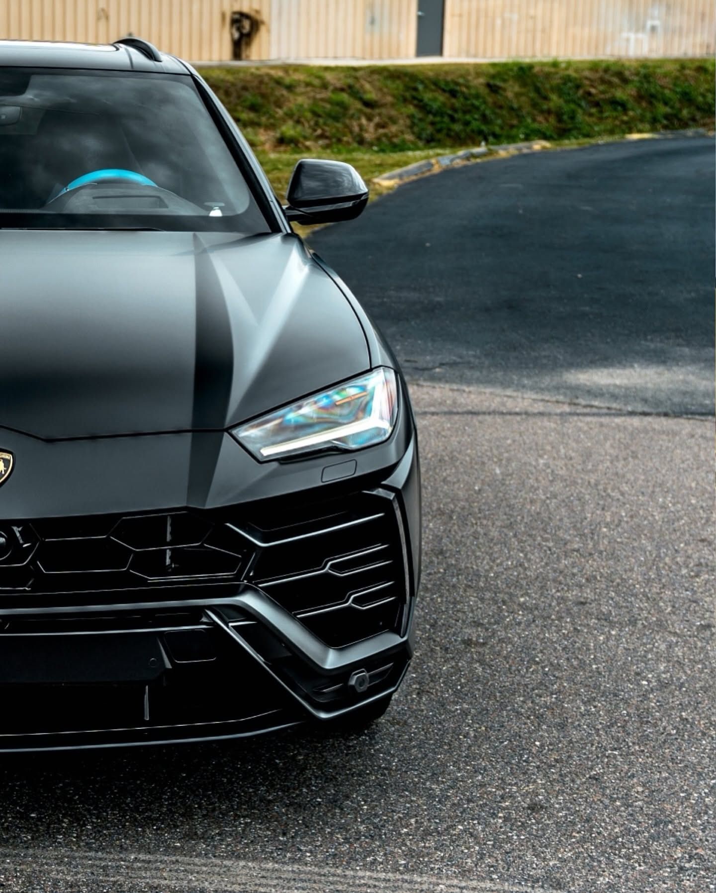 Front view of a black sports SUV parked on a paved driveway with trees in the background