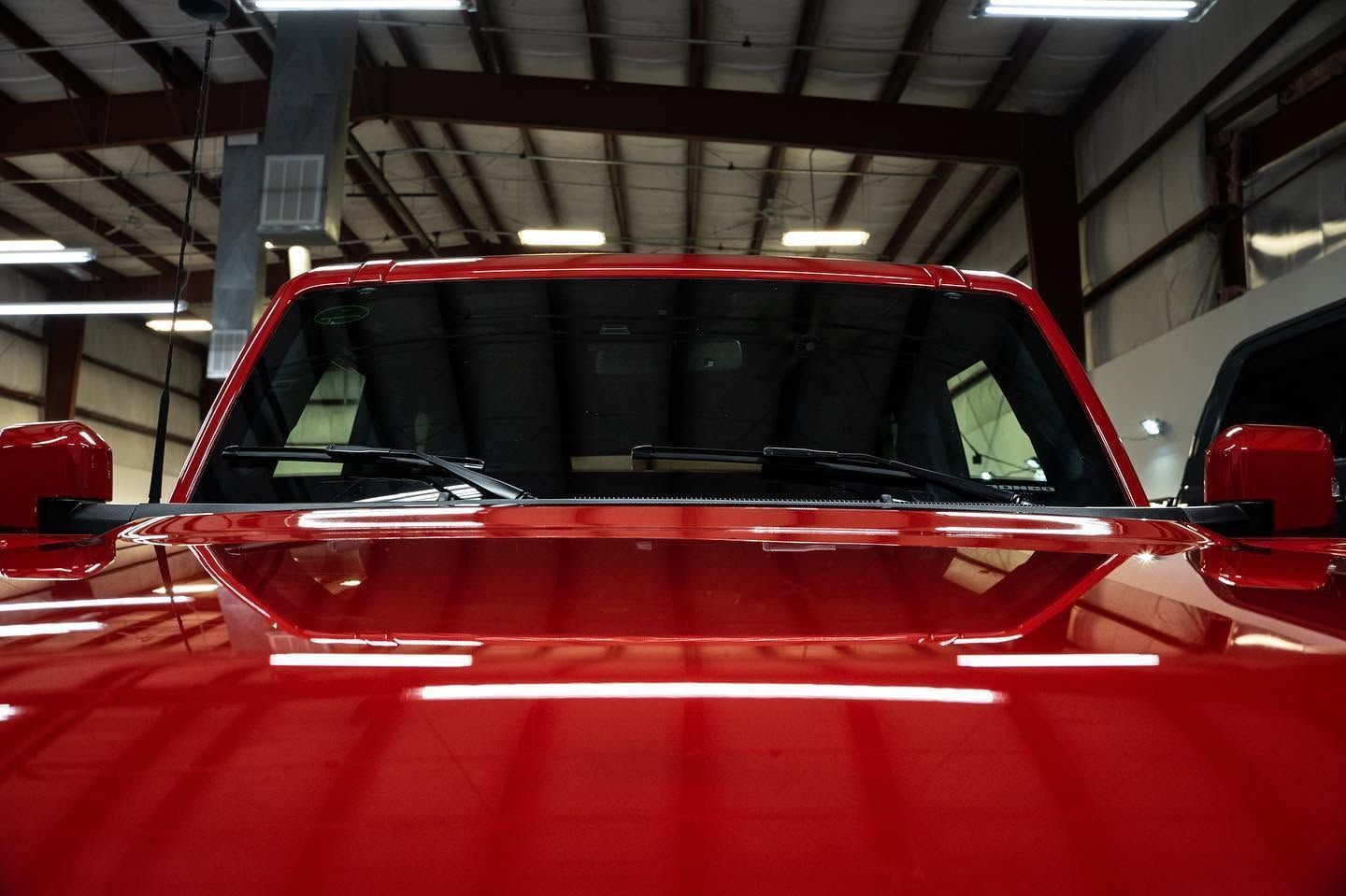 Red car parked inside a warehouse, front view under overhead lights