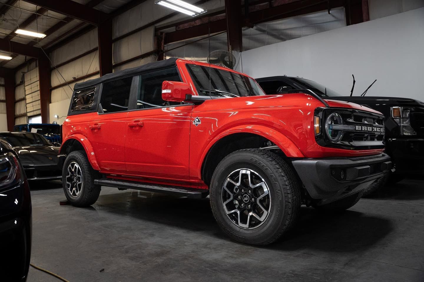 Red off-road SUV parked indoors in a warehouse-style garage, side view.