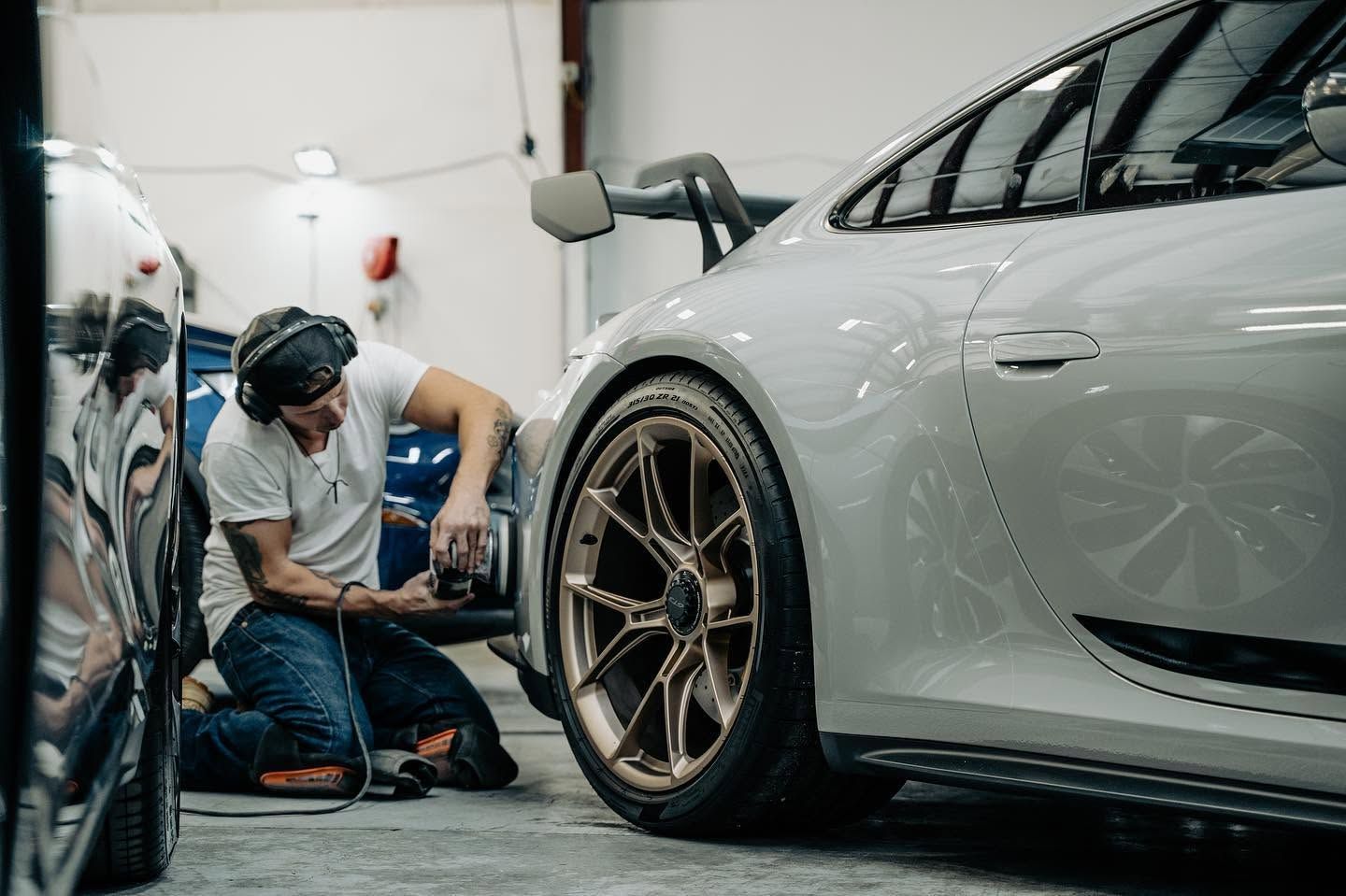 Mechanic tightening a wheel on a white sports car in a garage