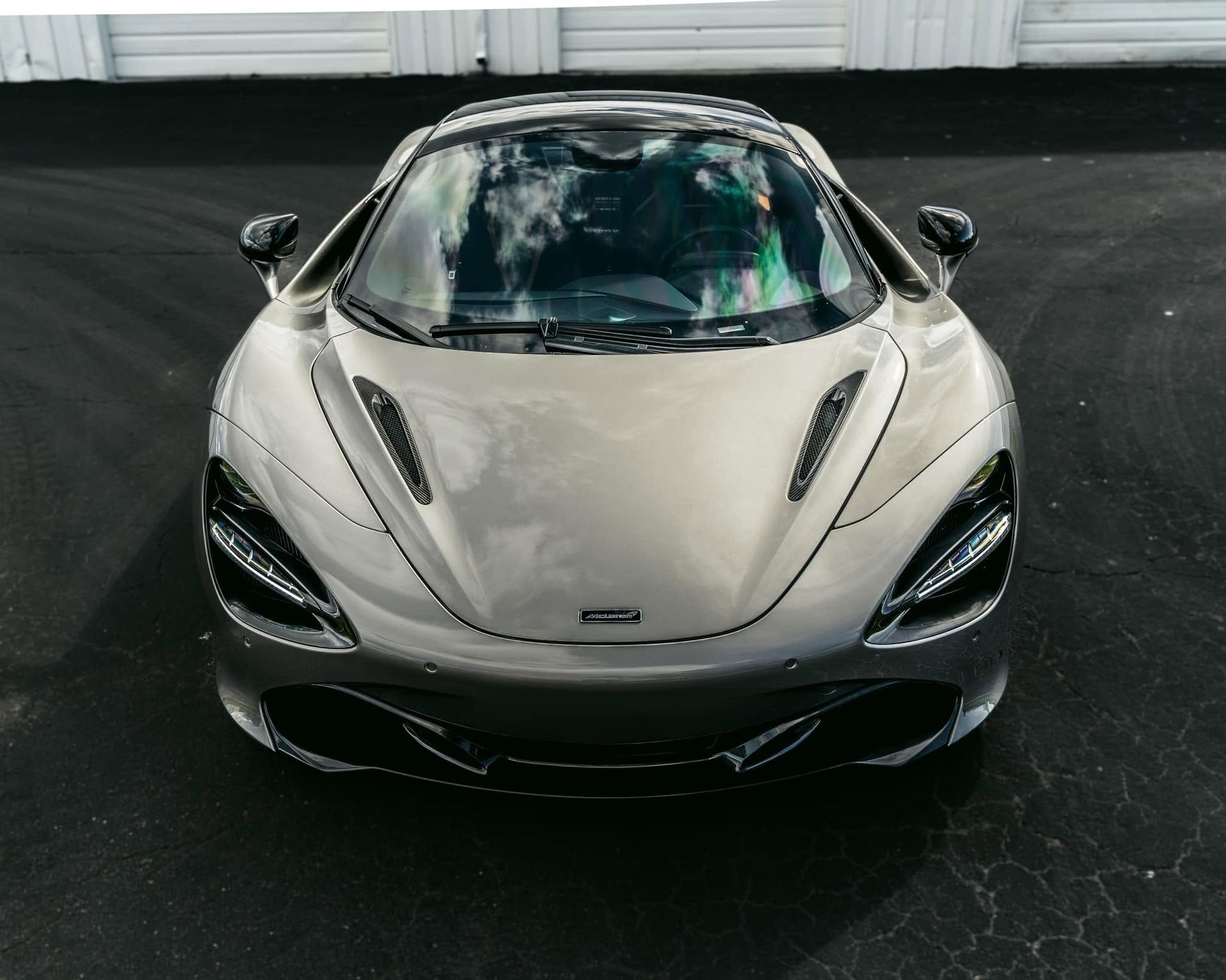 Front view of a silver sports car with sleek headlights on a dark showroom floor