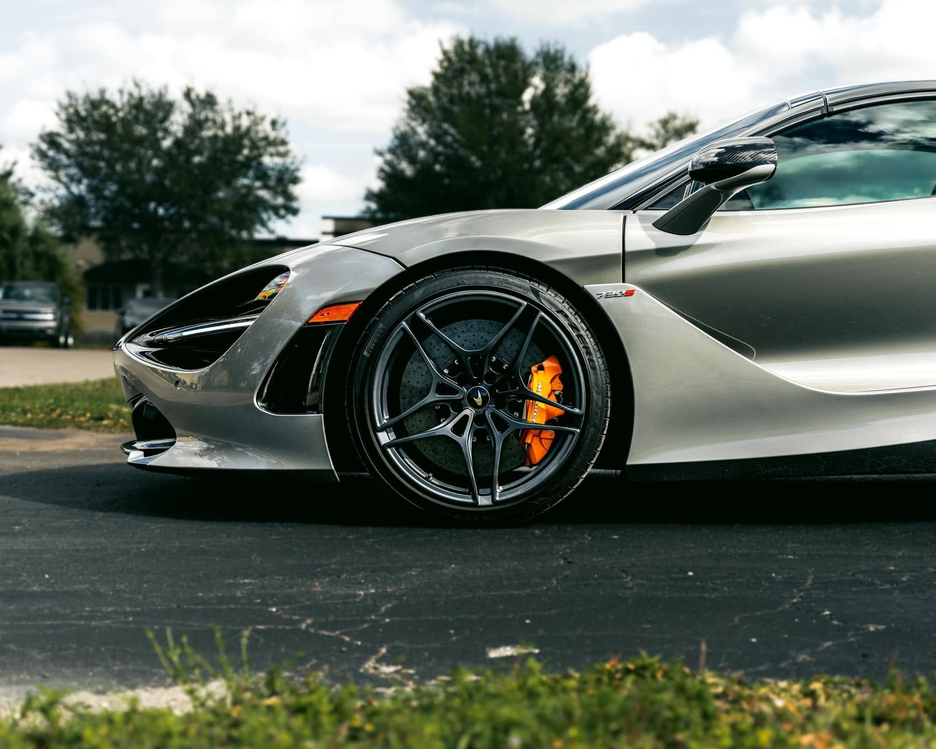 Silver sports car parked outdoors, side view with black wheels and orange brake calipers.