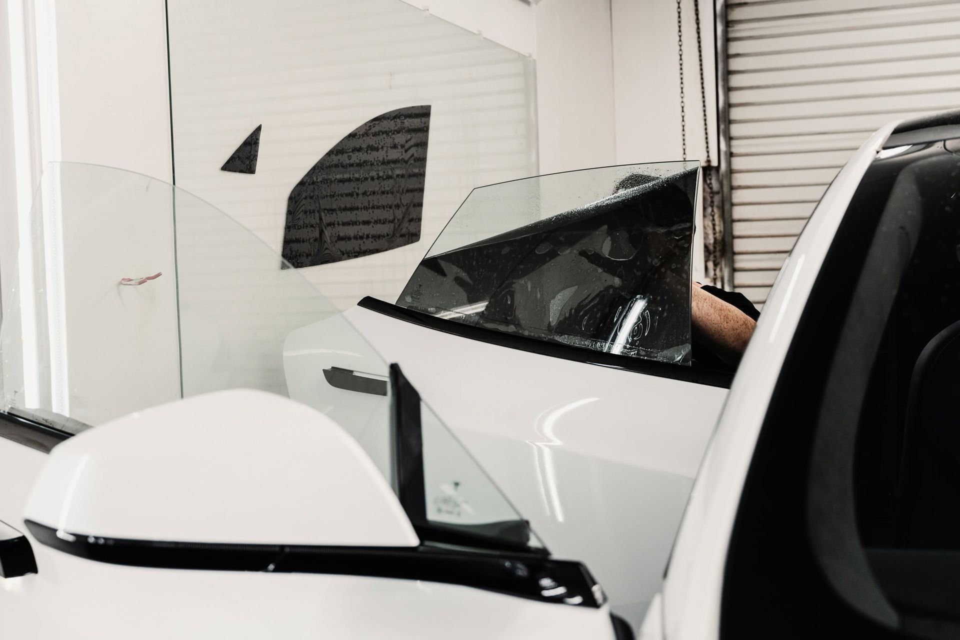 White sports car in a garage, viewed from the front beside a large wall graphic.