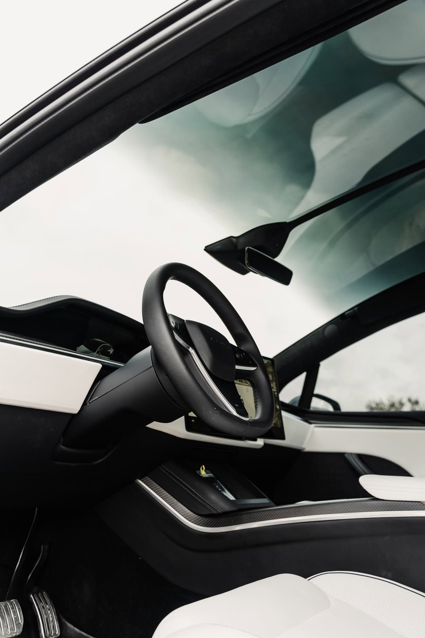 Luxury car interior with black leather seats, steering wheel, and sunroof under bright daylight