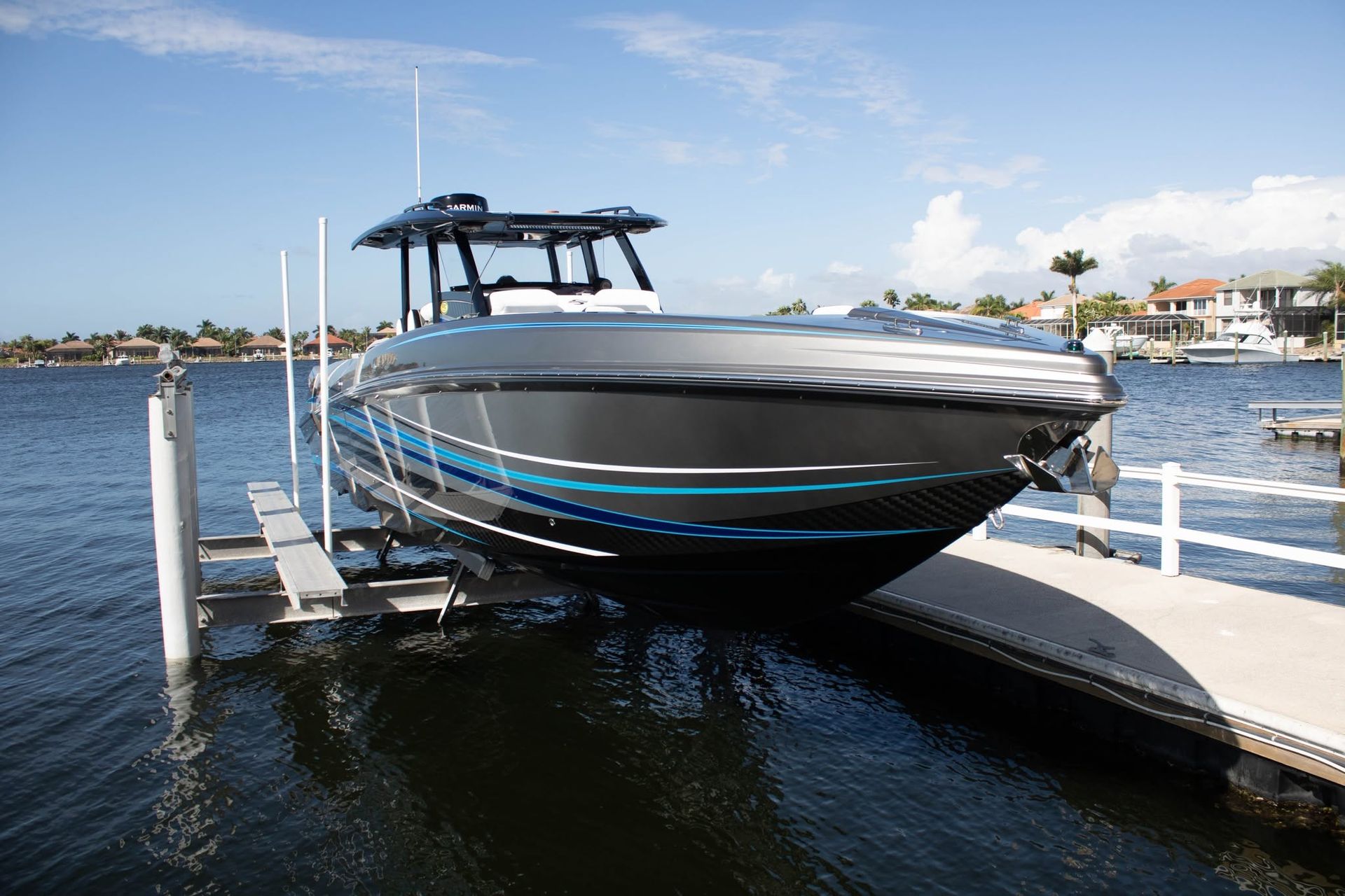 Black speedboat docked at a marina on calm water under a clear blue sky