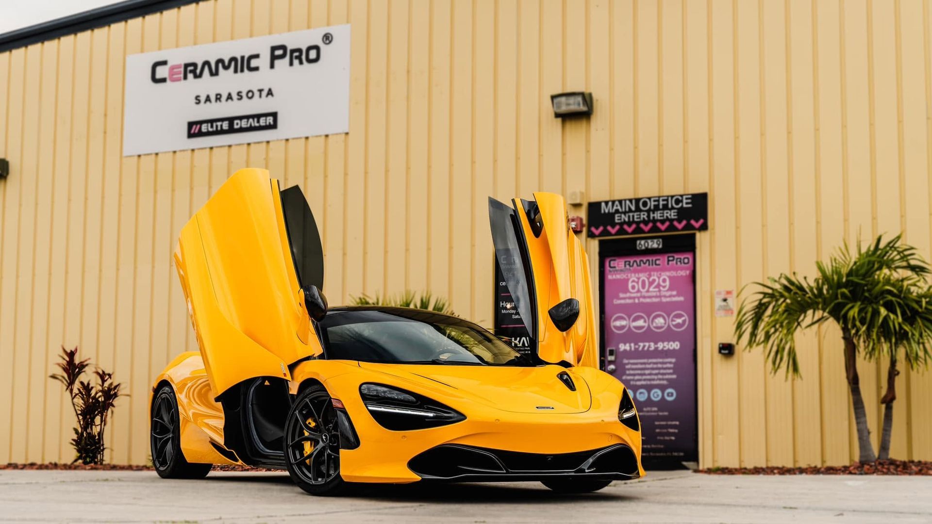 Yellow sports car with scissor doors open outside a Ceramic Pro building