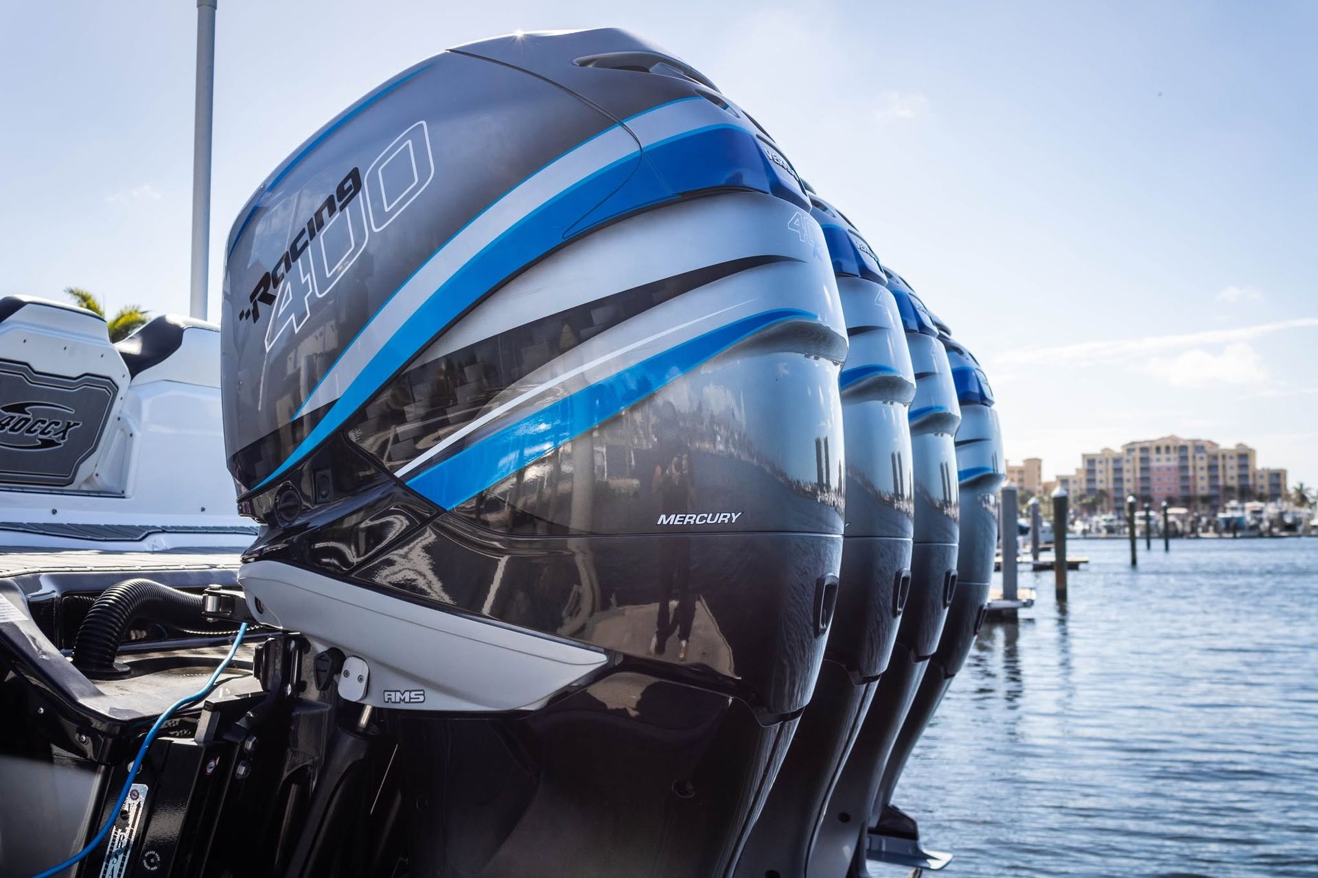 Blue-striped boat engines docked on calm water near a marina under clear sky