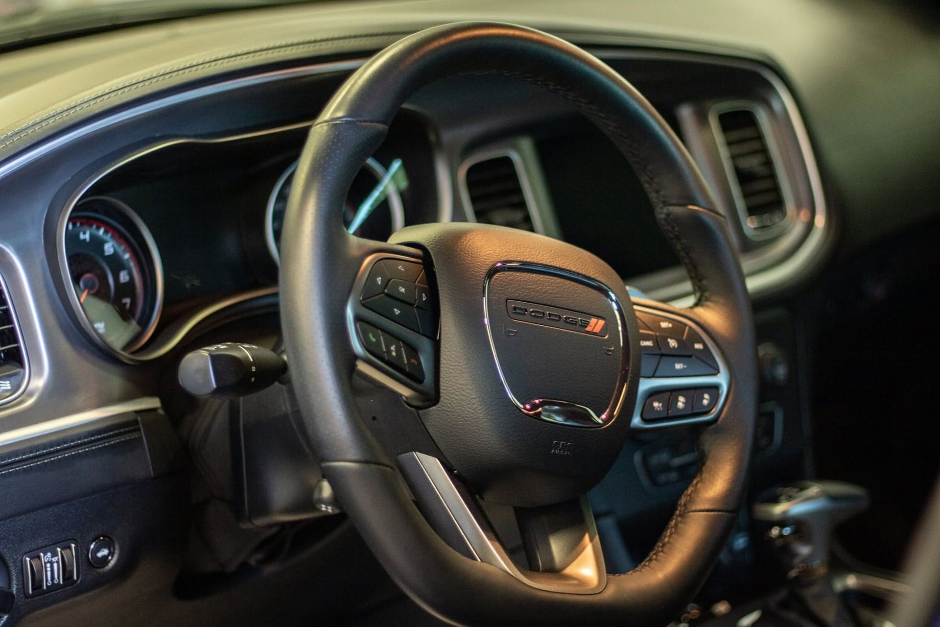 Car interior with steering wheel, dashboard gauges, and center console in black and tan trim