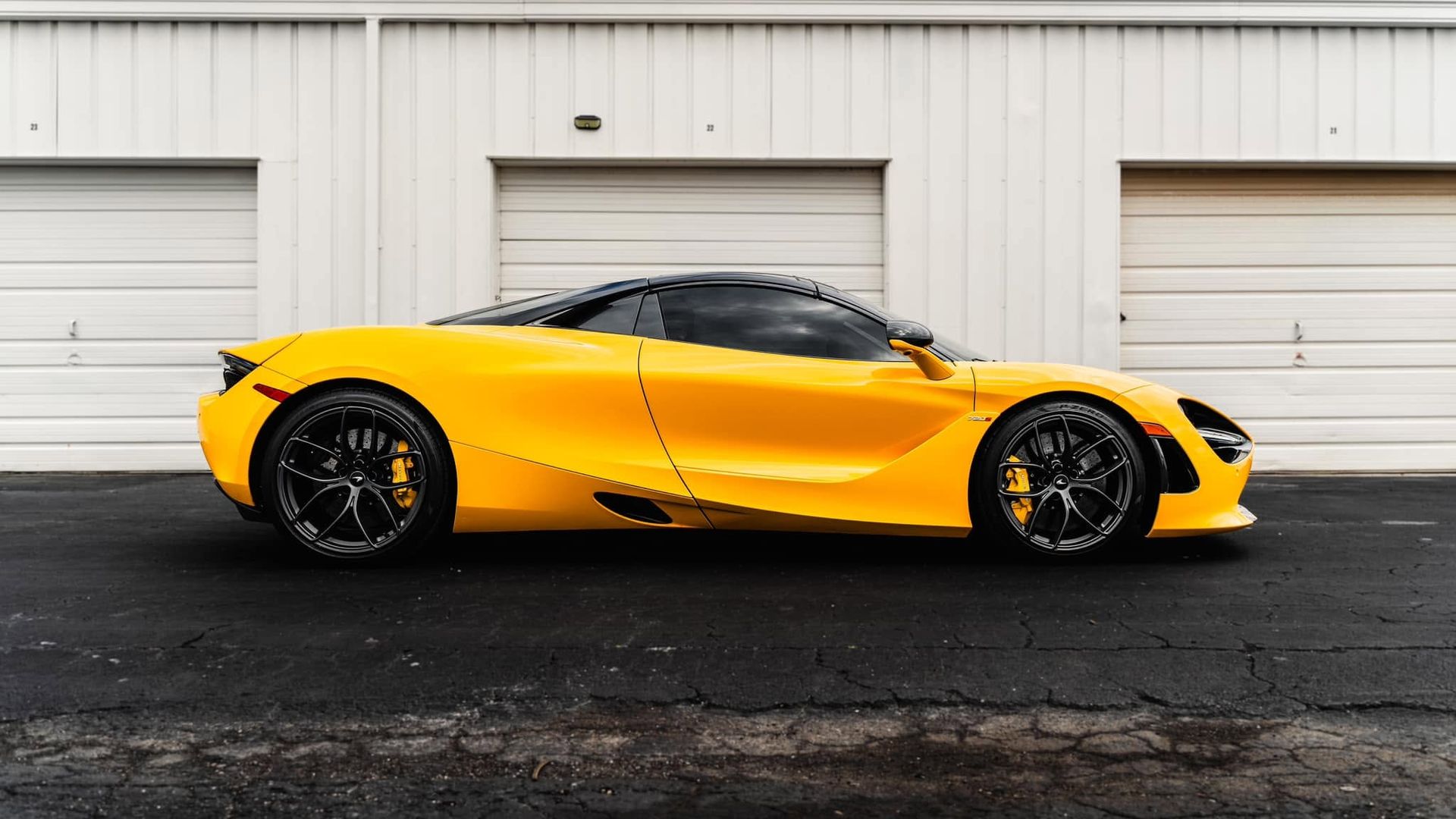 Yellow sports car parked side-on in front of a white garage door