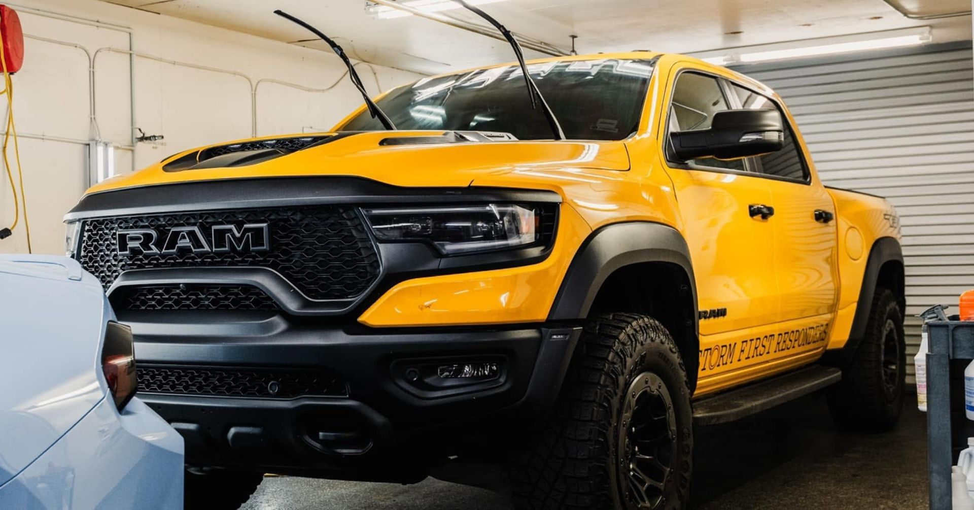 Yellow lifted truck in a garage, viewed from the front-left side.
