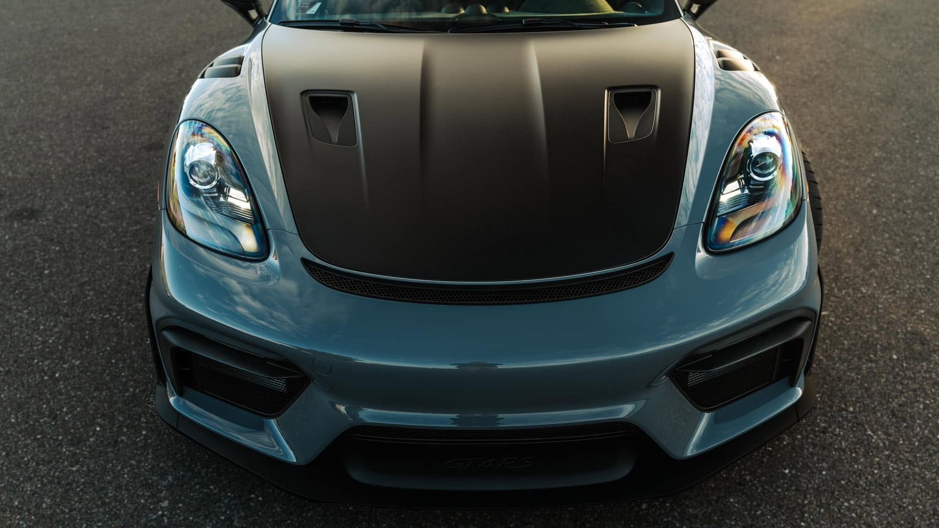 Front view of a blue sports car with a black hood on asphalt