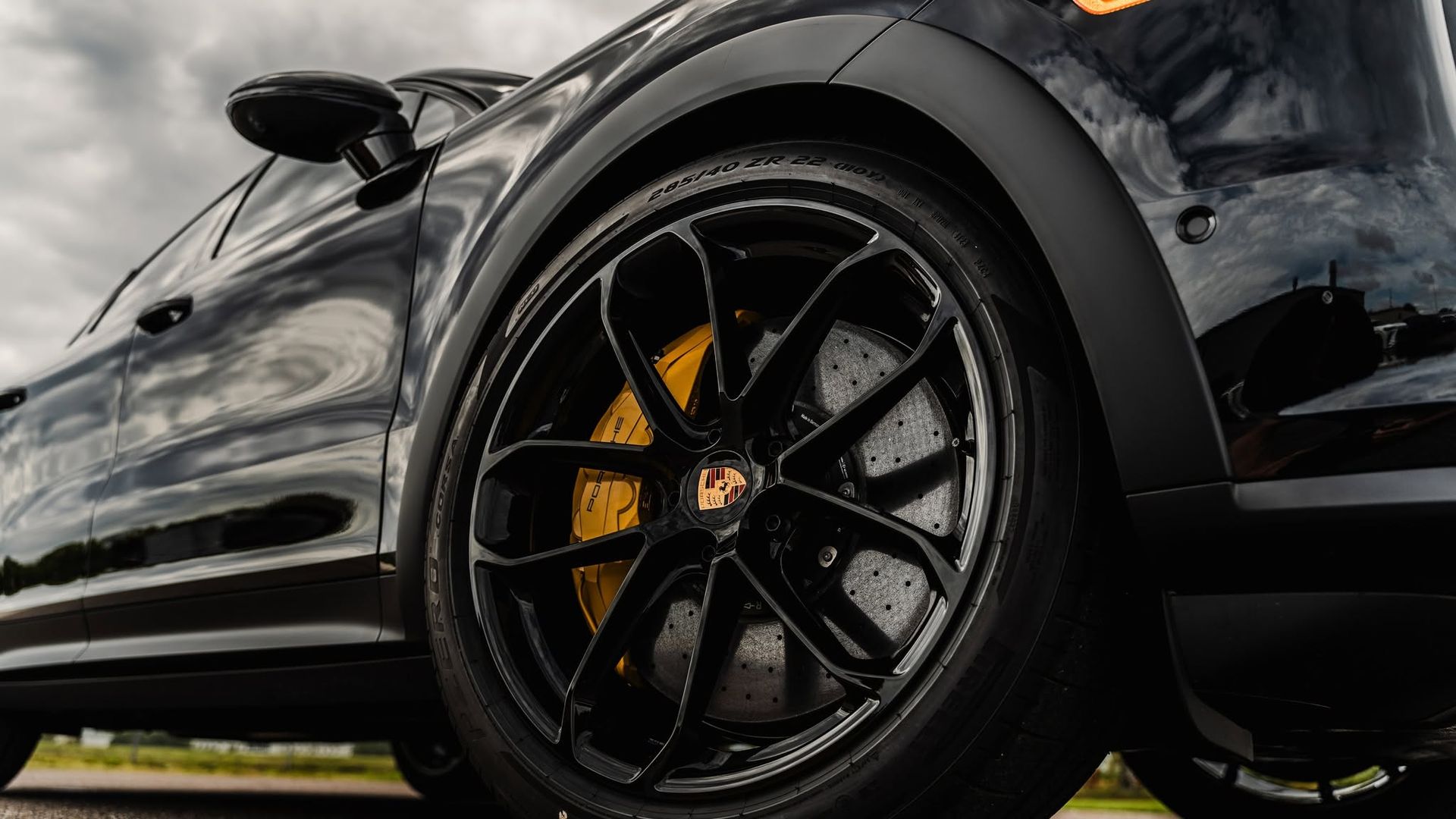 Close-up of a black sports car wheel with orange brake caliper on a glossy black body