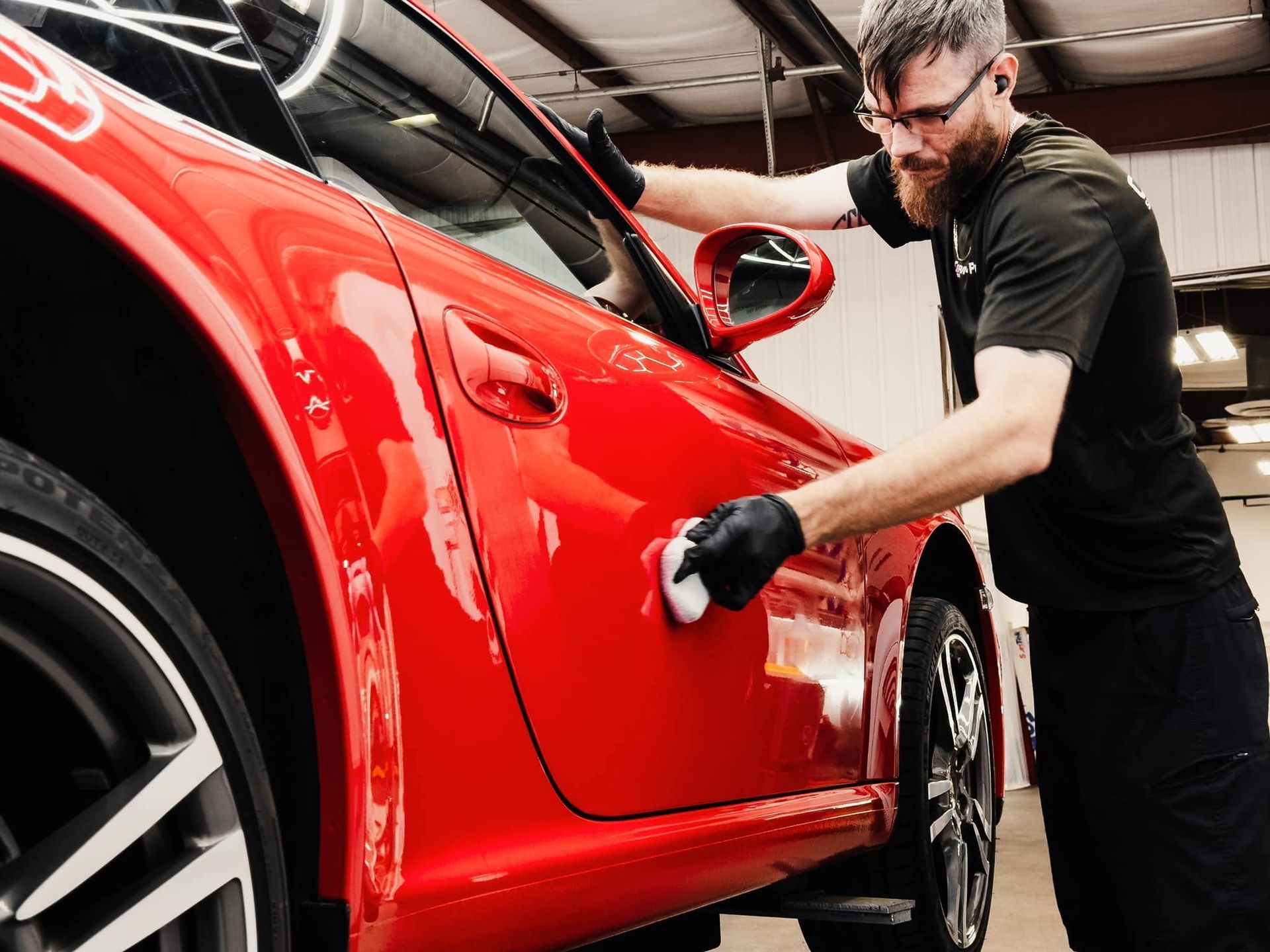 Mechanic polishing a red sports car in a garage