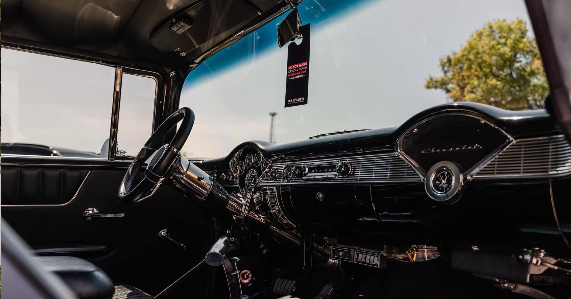 Vintage car interior with black dashboard, steering wheel, and front windshield view