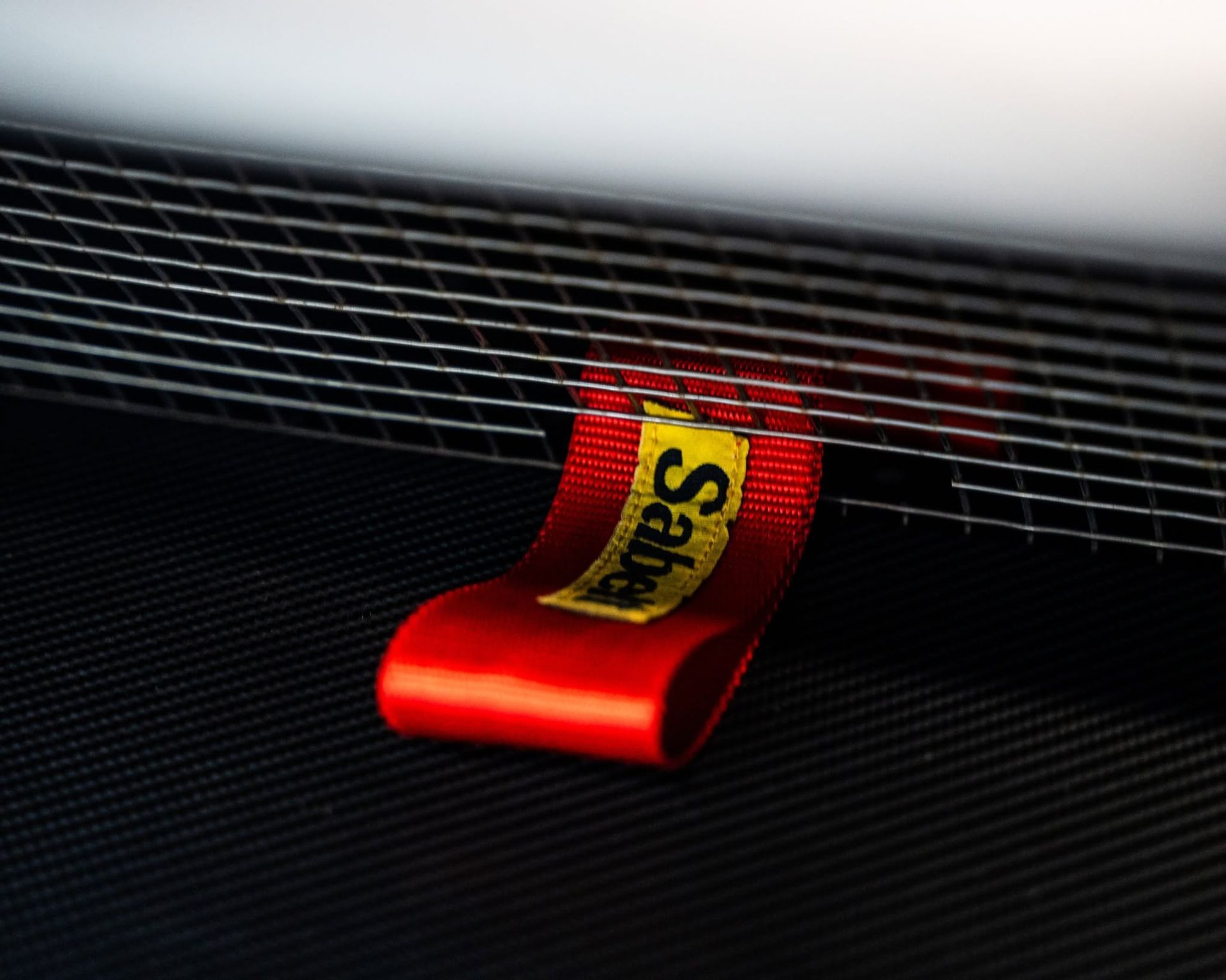 Red roll of tape with yellow label trapped under a wire mesh grille