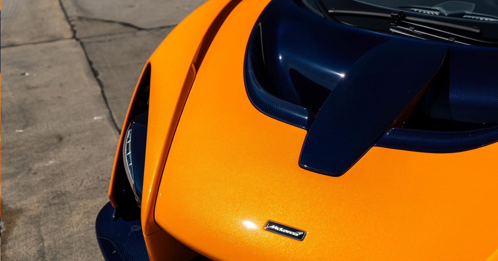 Orange sports car hood and windshield close-up on pavement