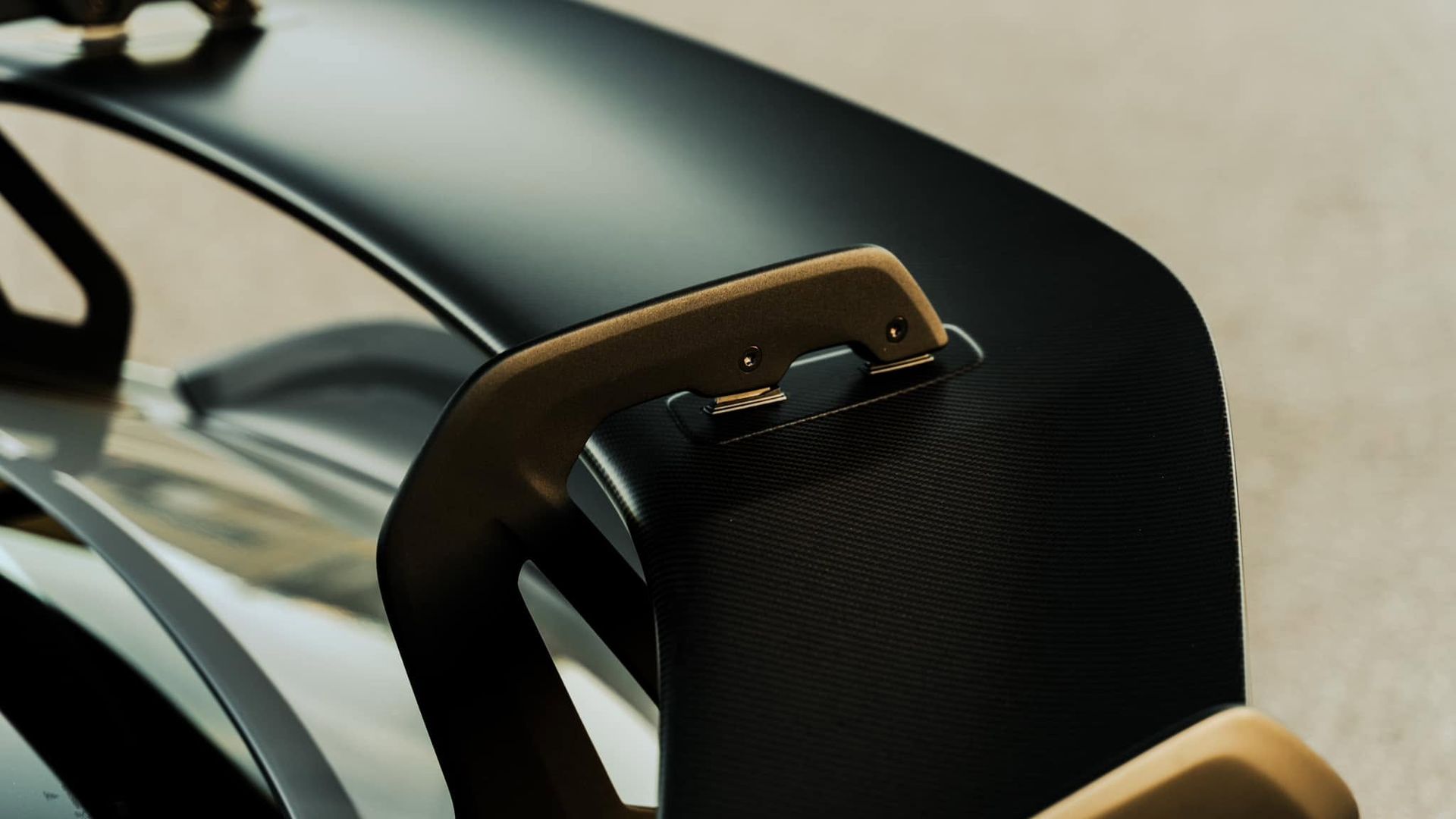 Close-up of a black and tan chair armrest with curved metal frame and textured fabric