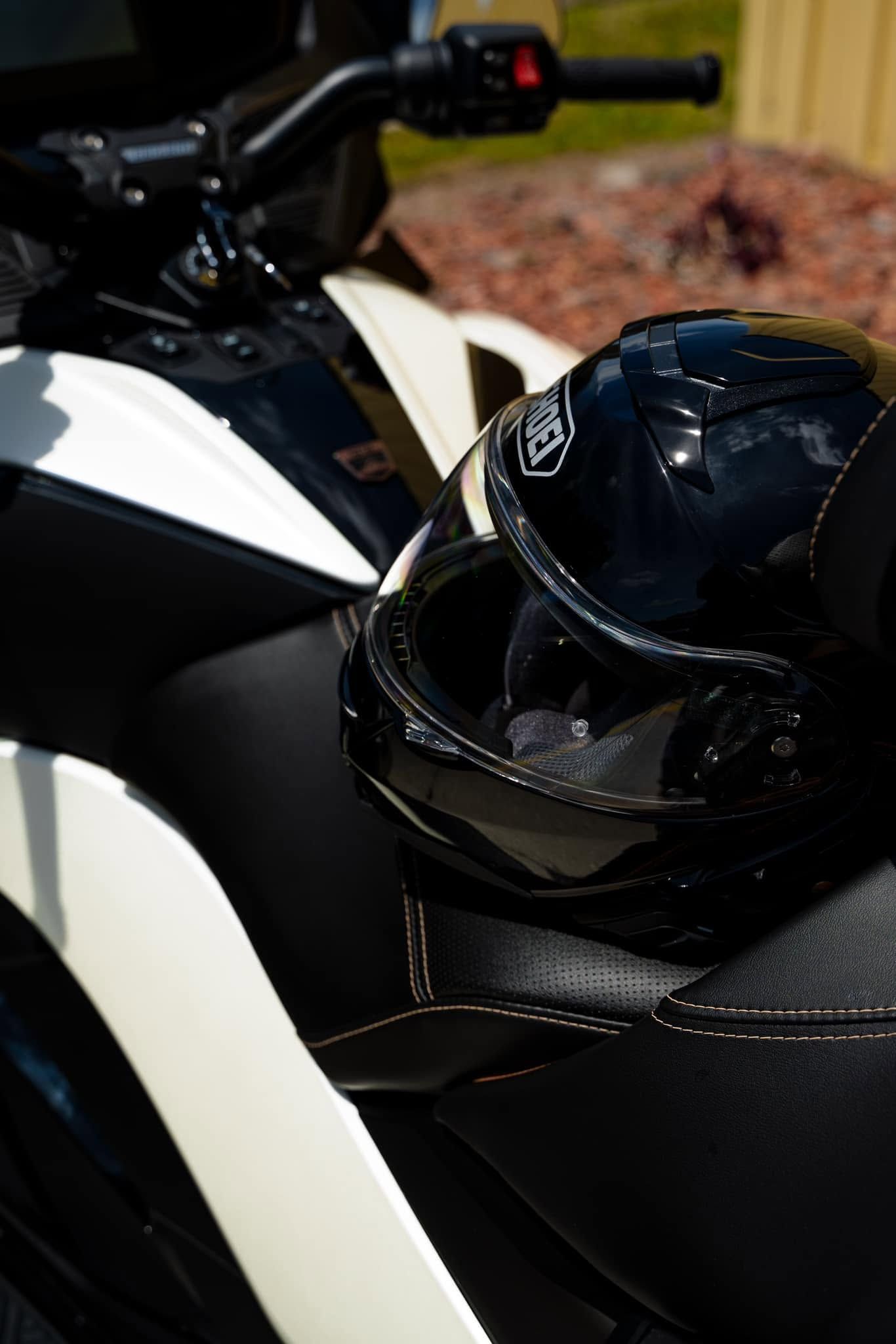 Black motorcycle with a glossy black helmet resting on the seat, indoors on a striped surface.