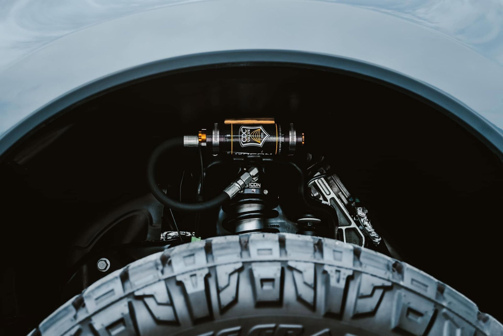 Close-up of a car wheel and suspension inside a dark wheel well
