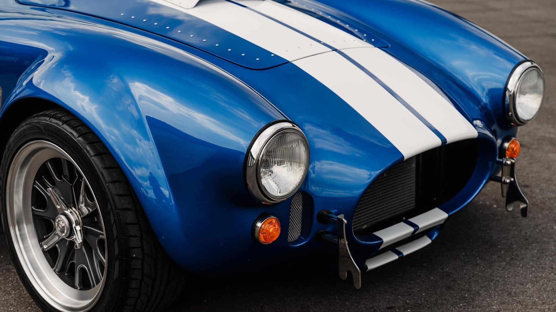 Blue sports car with white racing stripes, close-up of the front end and headlights