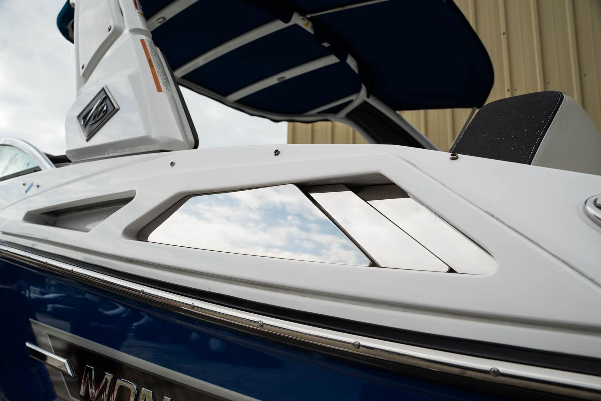 White and navy boat with tinted windows and a blue canopy at a marina